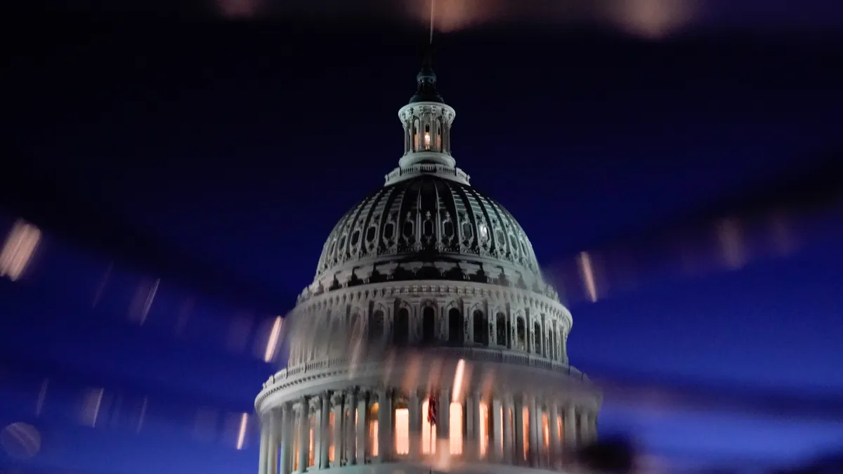 The U.S. Capitol dome is seen reflected in a puddle in Washington