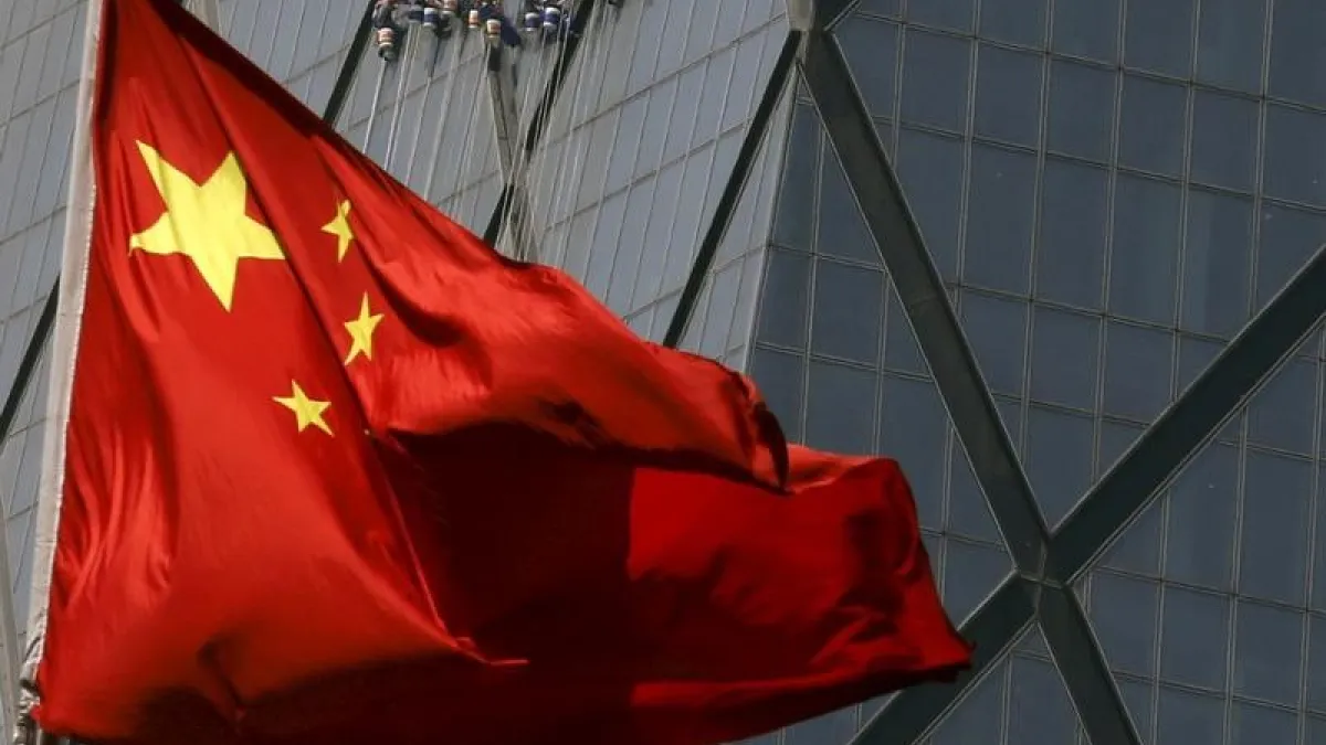 Workers cleaning windows of a building are seen behind China's national flag at a commercial district in Beijing April 20,  2015.  REUTERS/Kim Kyung-Hoon 