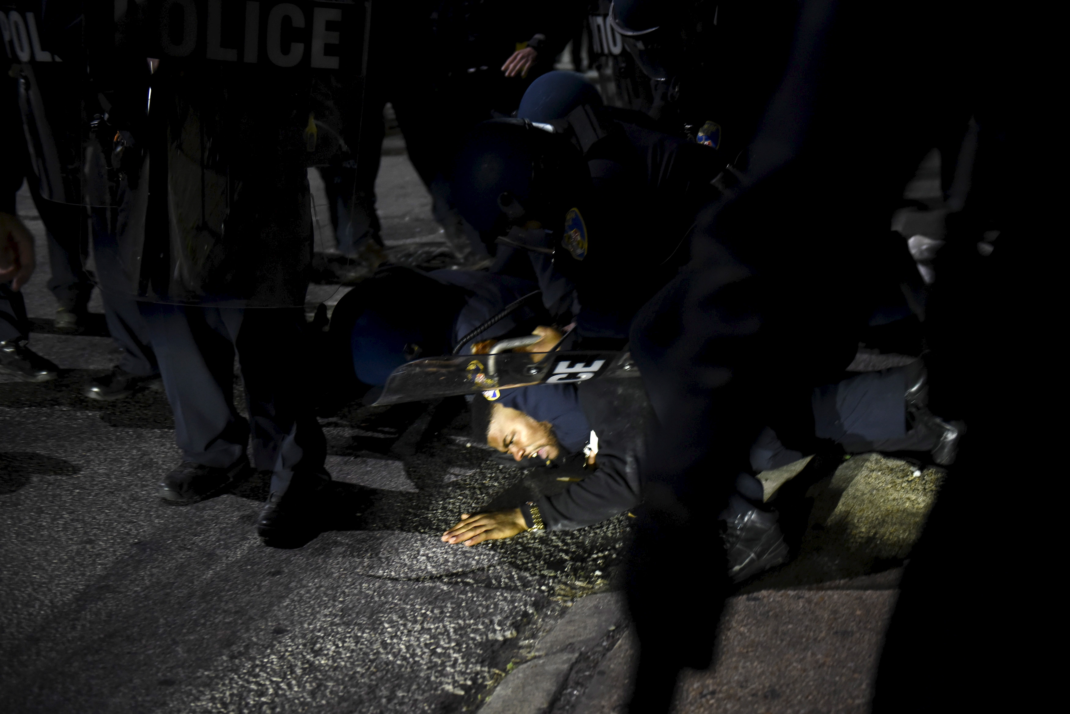 Law enforcement officers detain a demonstrator on Gilmore Avenue near Baltimore Police Department Western District during a protest against the death of Gray in police custody, in Baltimore