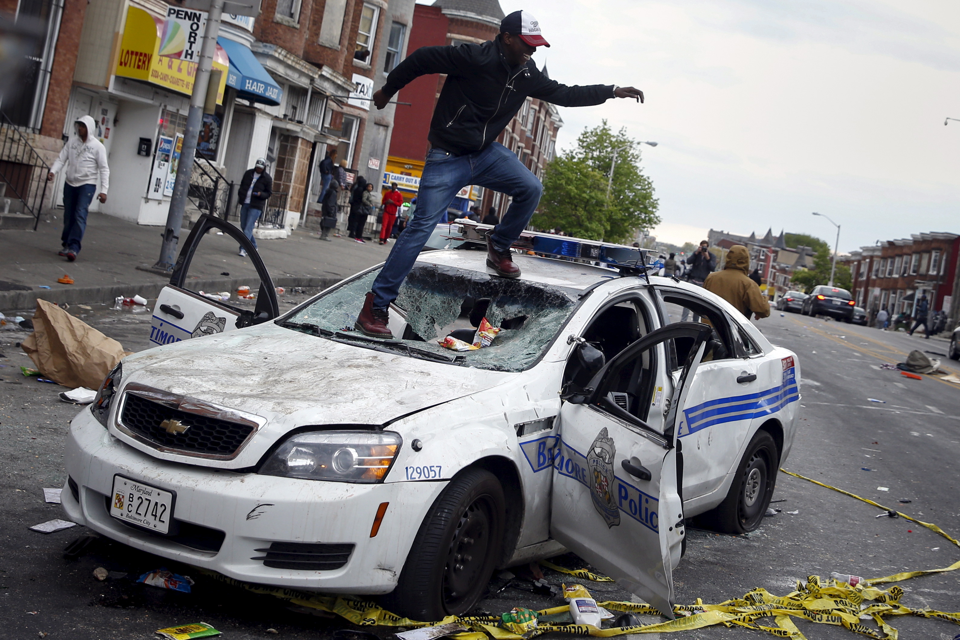 Demonstrators jump on a damaged Baltimore police department vehicle during clashes in Baltimore