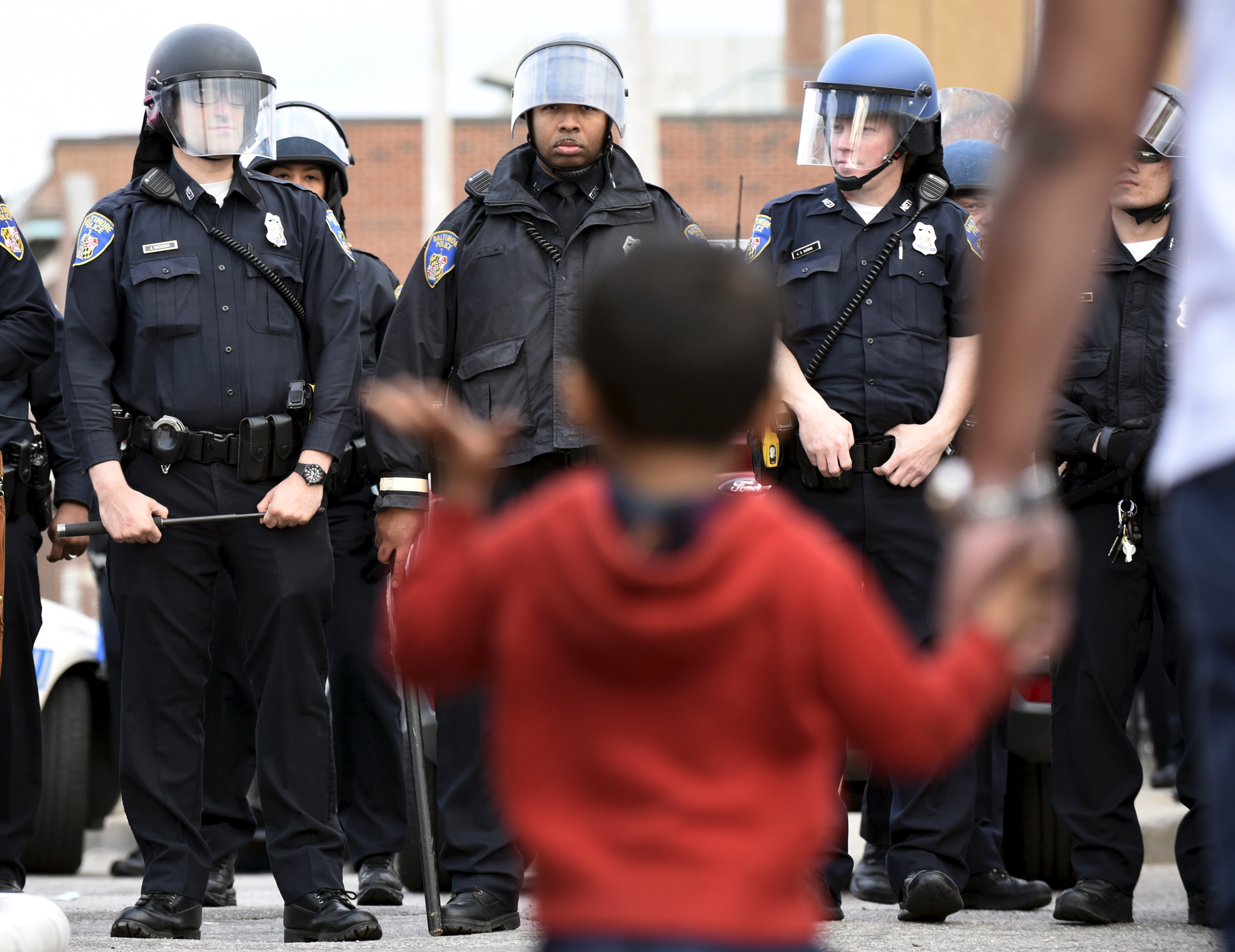 A child waves at law enforcement officers on Pennsylvania Avenue in Baltimore