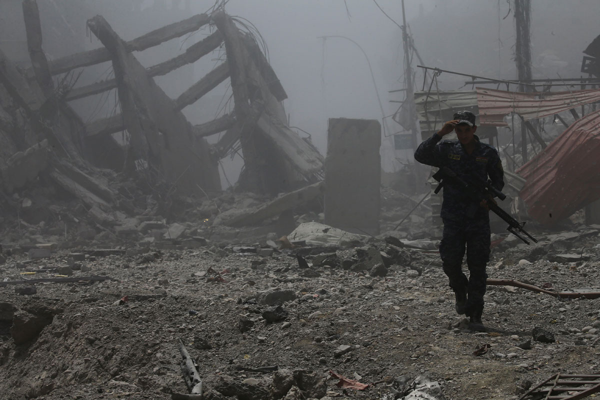 A member of Iraqi Federal police walks along destroyed buildings from clashes in the Old City of Mosul