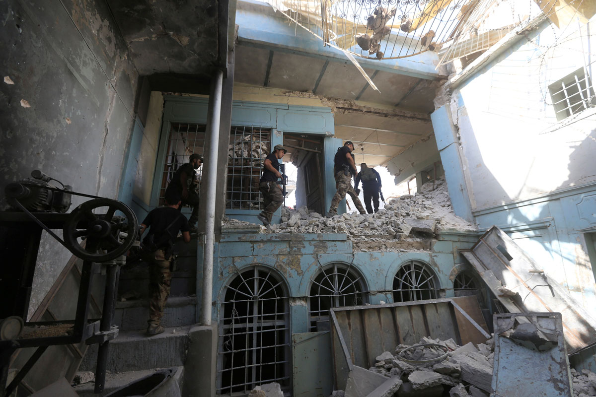 Iraqi Counter Terrorism Service (CTS) personnel walk in a destroyed building in the Old City of Mosul, Iraq