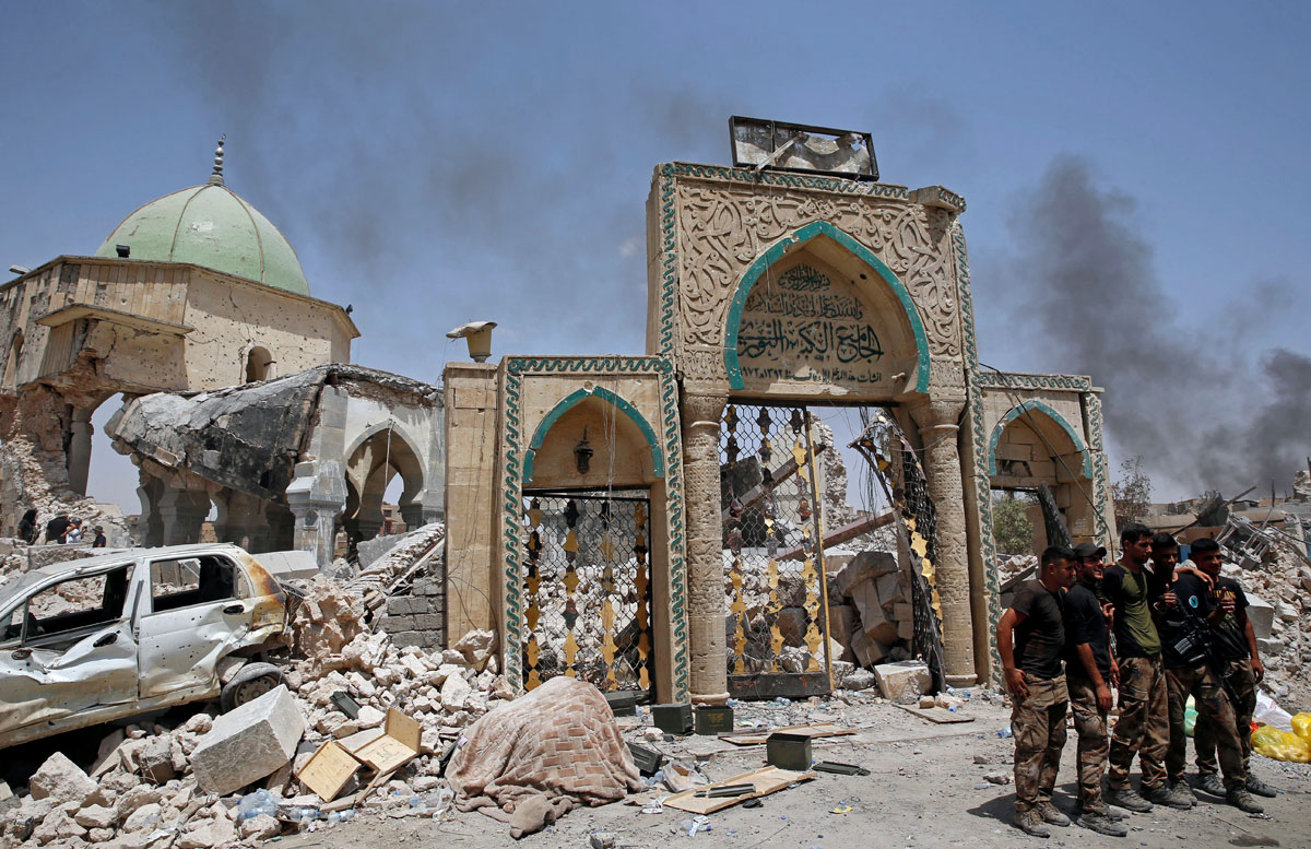 Members of Iraqi forces pose in front of the ruined Grand al-Nuri mosque in the Old City in Mosul