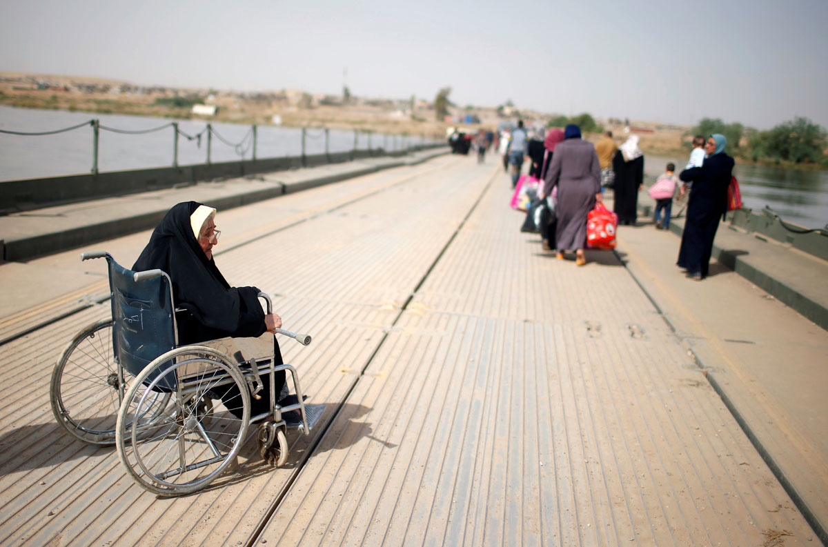 displaced Iraqi woman waits for her son to cross the Tigris River as Iraqi forces battle with Islamic State militants, in western Mosul