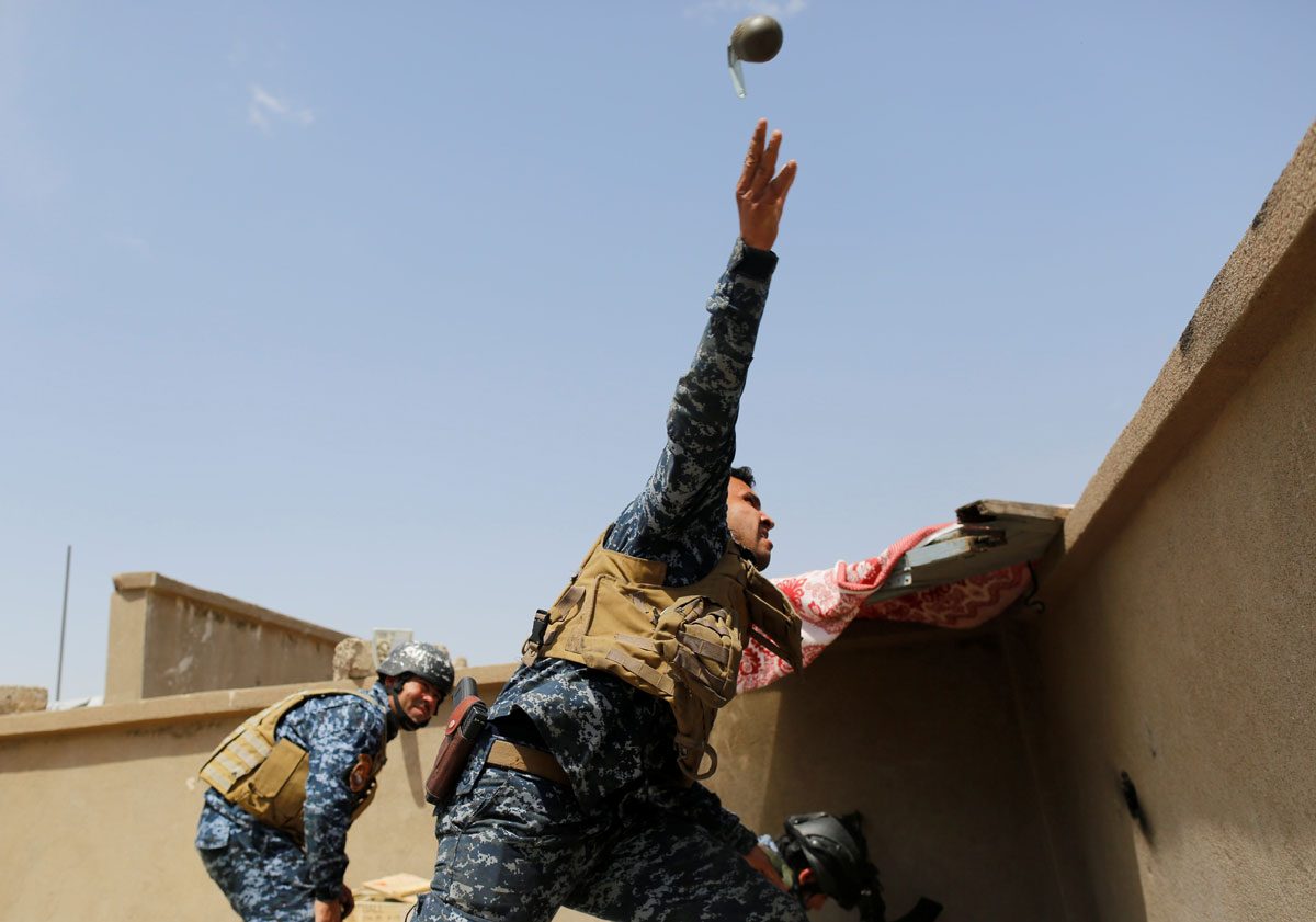 A members of the Iraqi Federal Police throws a hand grenade during clashes with the Islamic State fighters in western Mosul