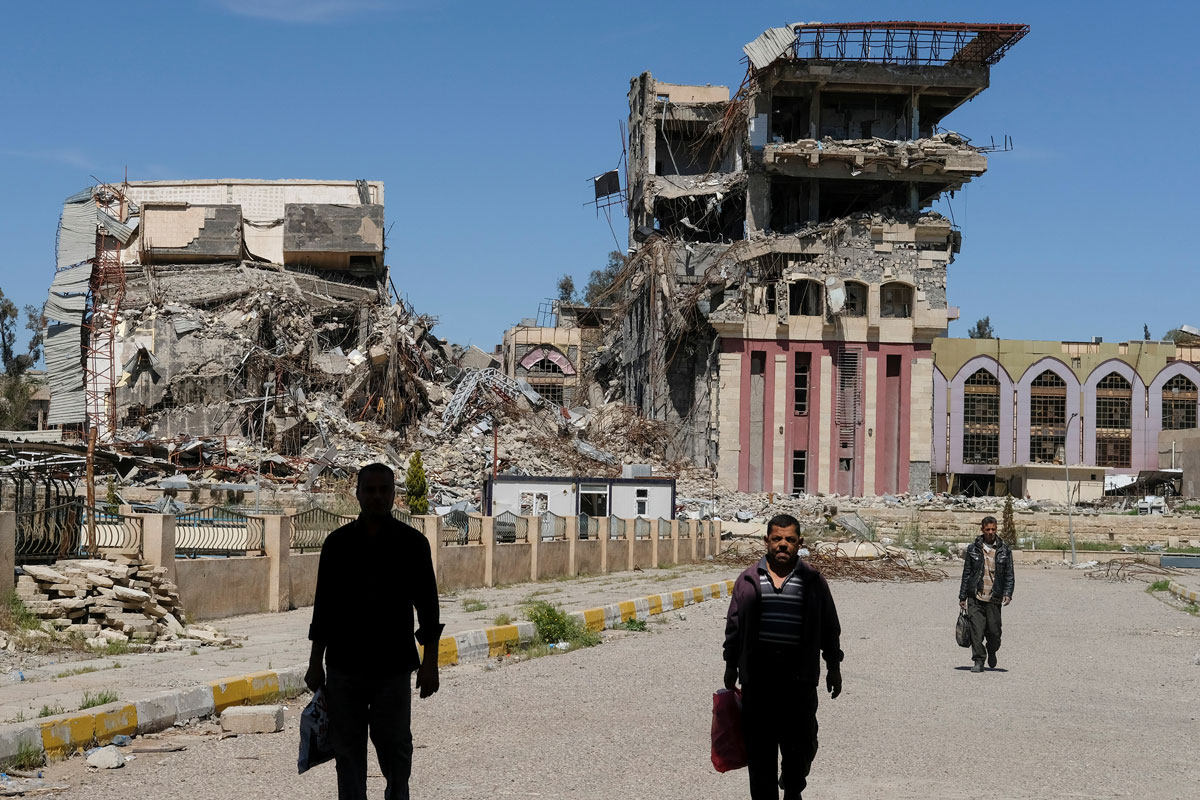 People walk in front of remains of University of Mosul in Mosul