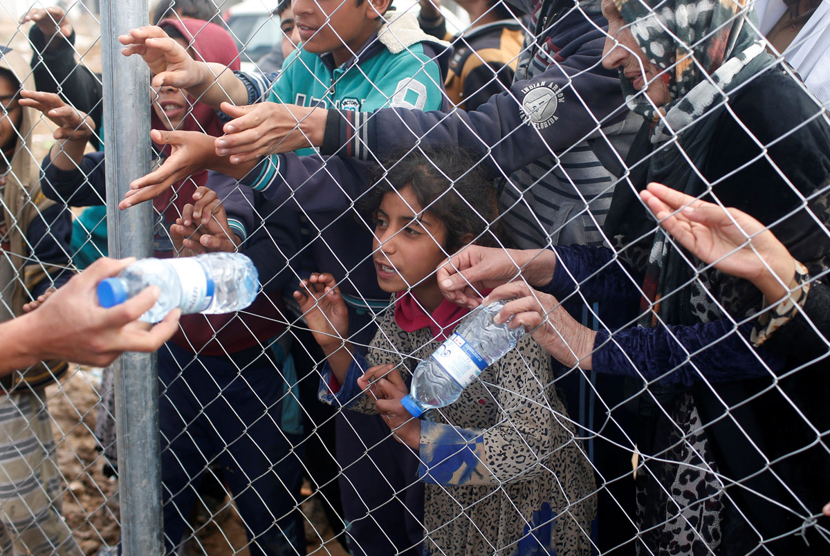 Displaced Iraqis who had fled their homes reach to get water before entering at Hammam al-Alil camp south of Mosul