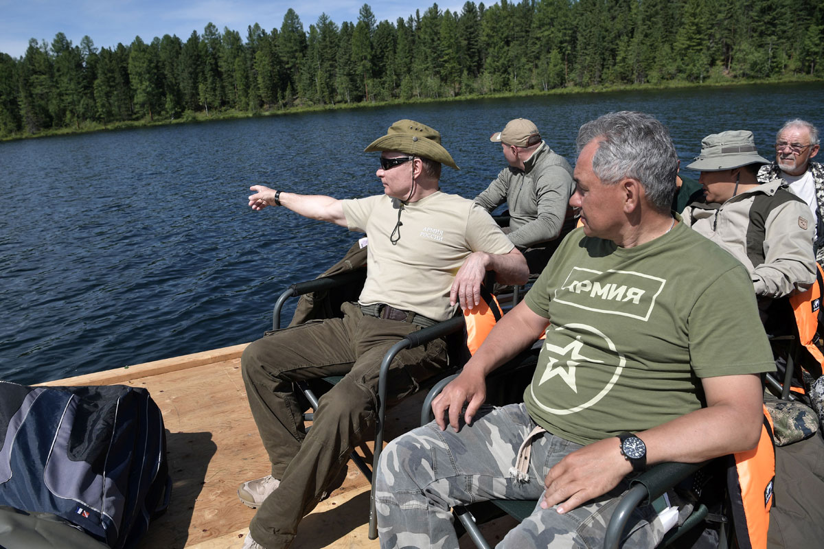 Russian President Vladimir Putin and Defence Minister Sergei Shoigu rest after fishing during the hunting and fishing trip which took place on August 1-3 in the republic of Tyva in southern Siberia