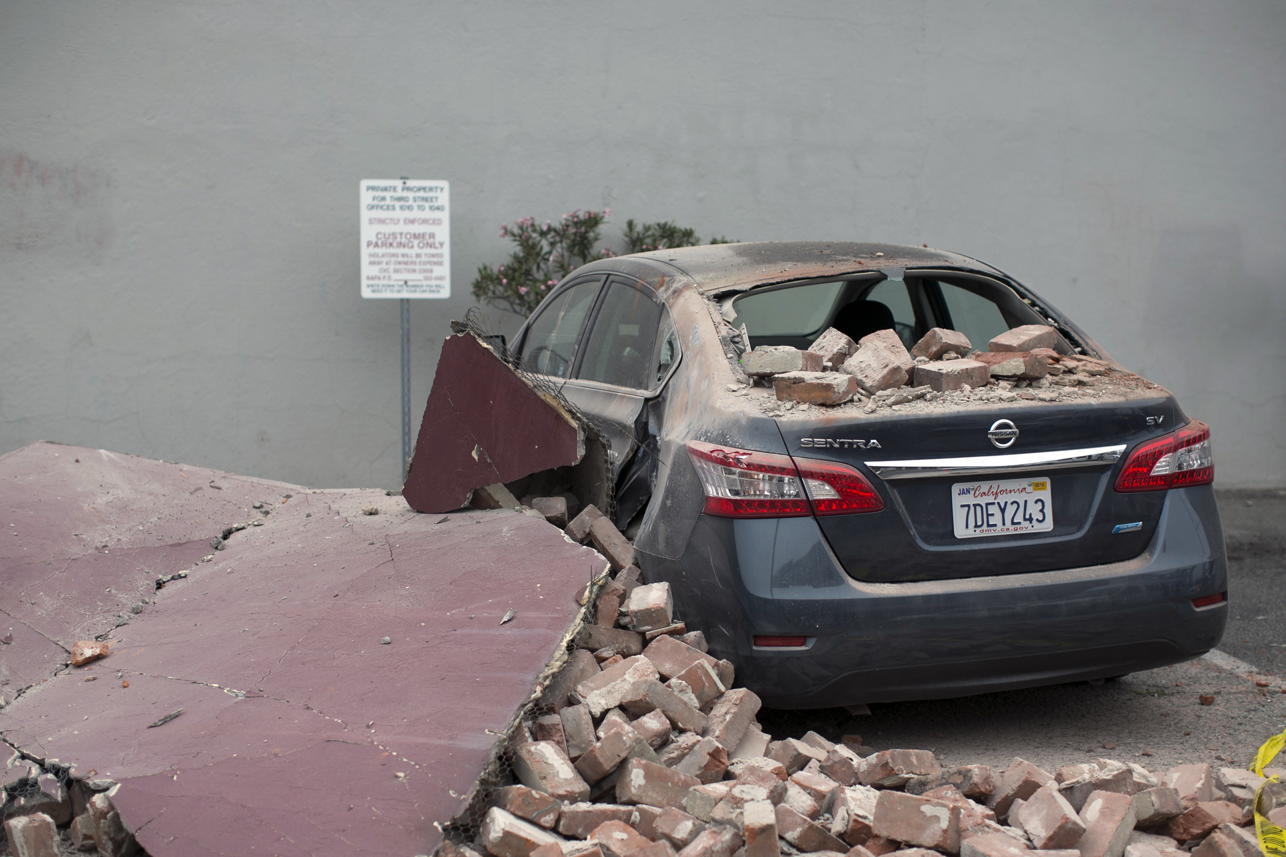 Car damaged by bricks falling during an earthquake is seen next to a downtown building in Napa, California