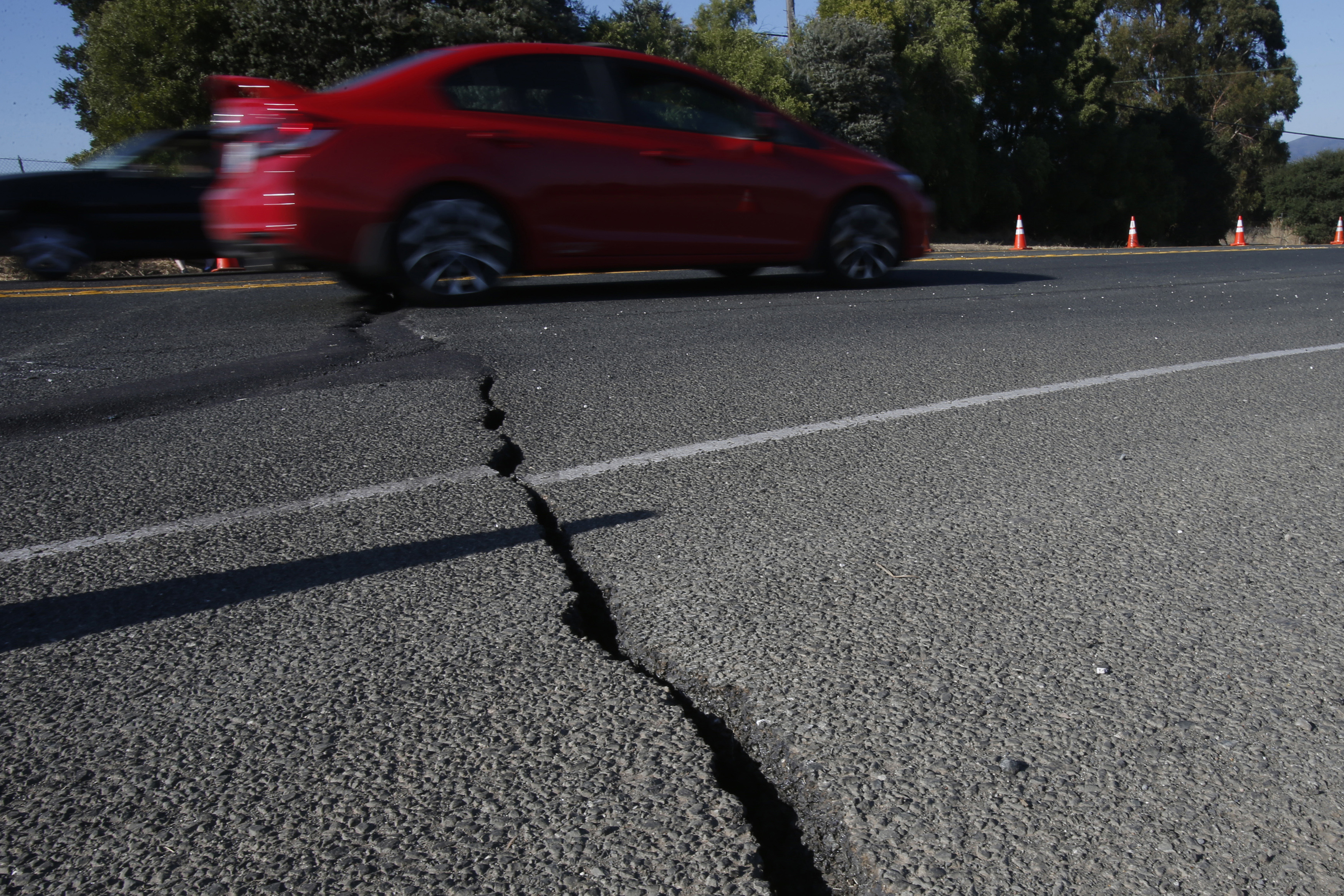 A car drives over cracked asphalt along Highway 12 after a 6.0 earthquake in Napa