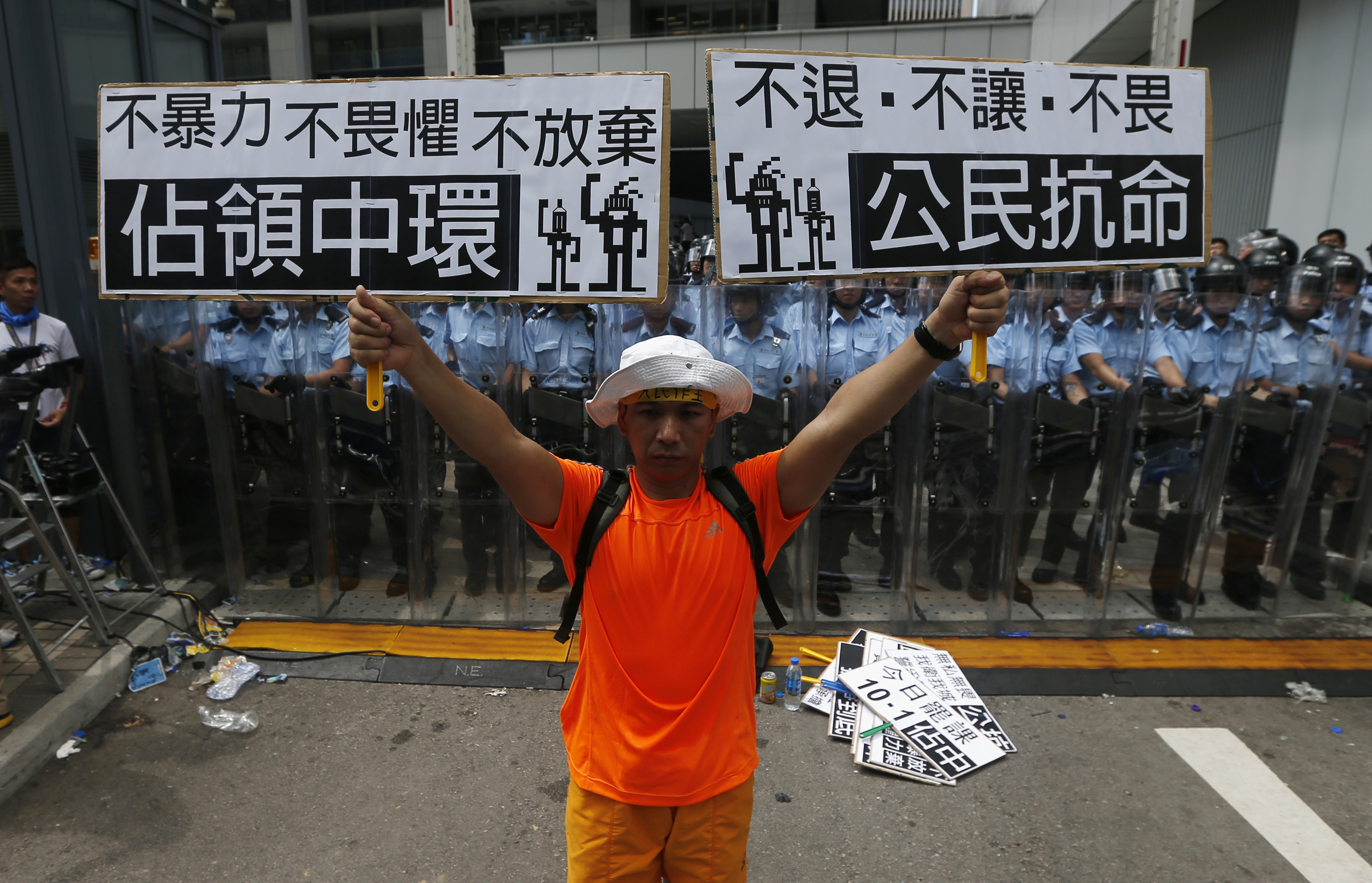 A protester holds up placards in front of a line of riot police outside government headquarters in Hong Kong