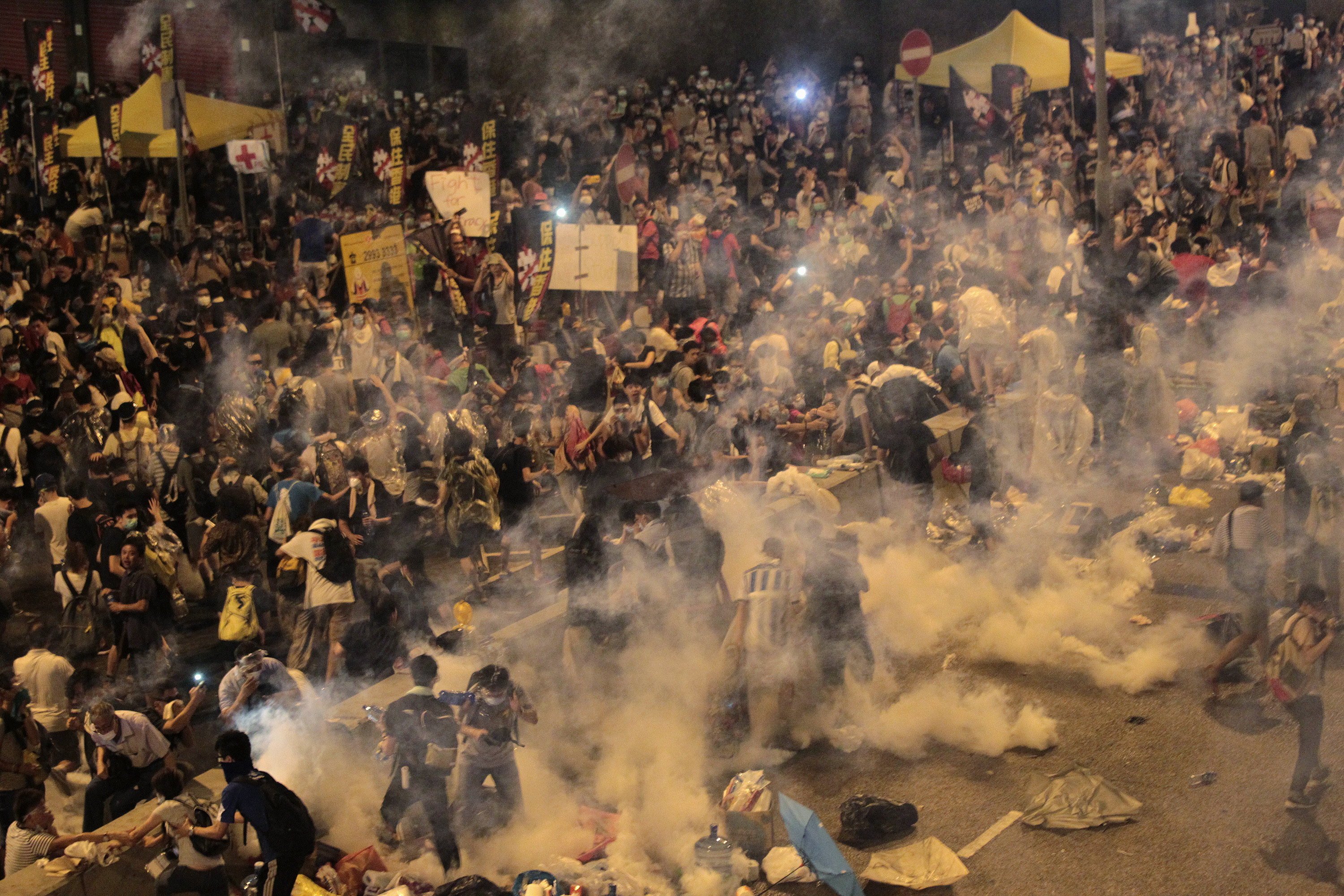 Protesters flee from teargas fired by riot police, during clashes after thousands of protesters blocked the main street to the financial Central district outside the government headquarters in Hong Kong