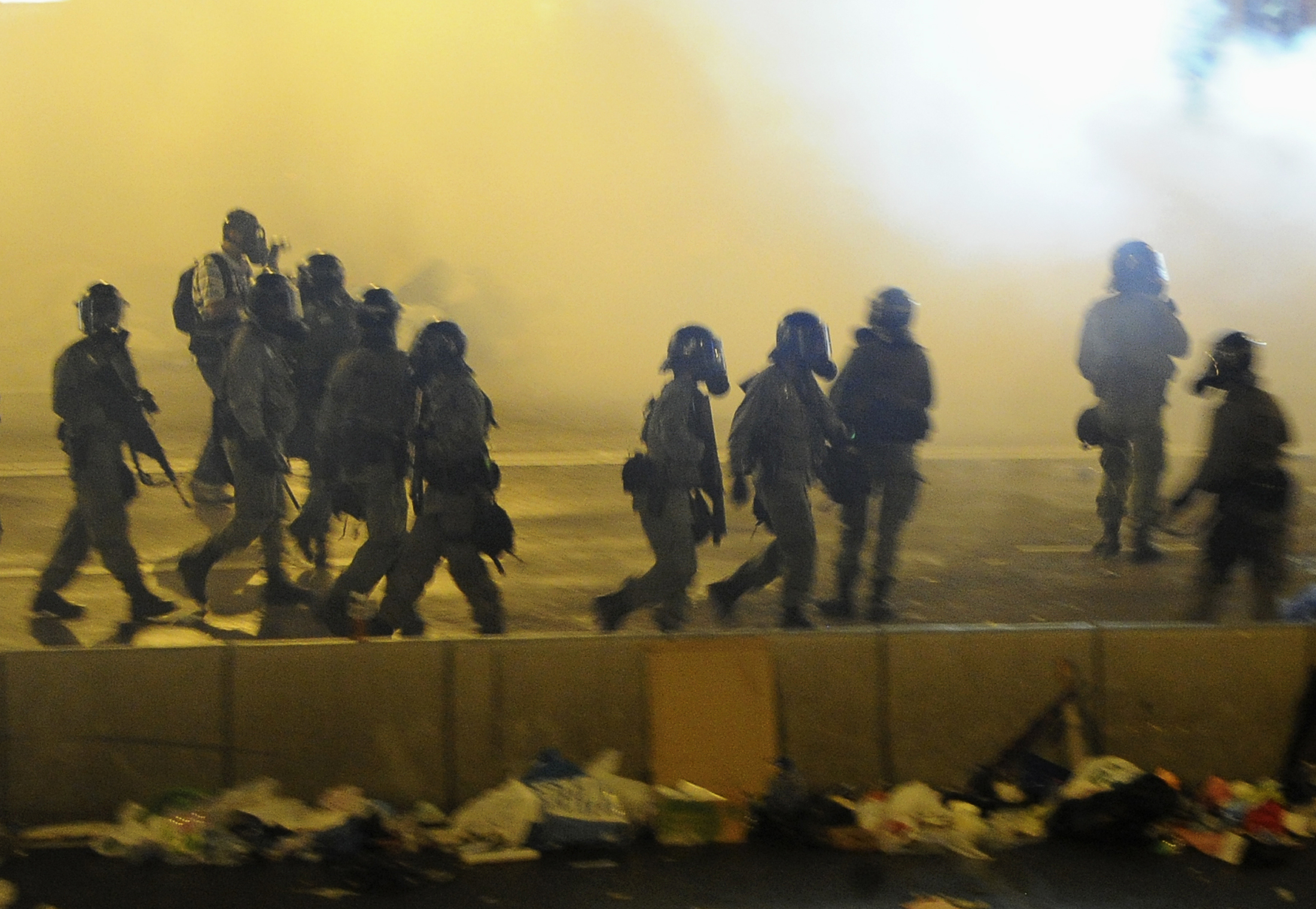 Riot police walk in between tear gas to disperse protesters after thousands of protesters blocked the main street to the financial Central district outside the government headquarters in Hong Kong