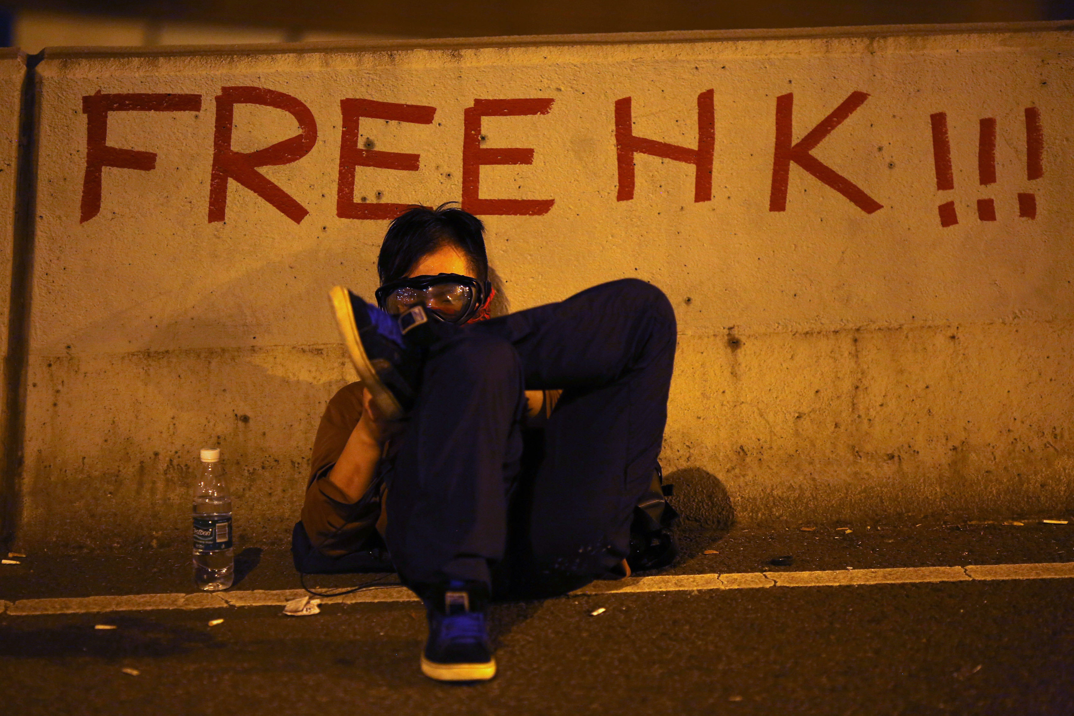 A protester sits as he blocks the main street to the financial Central district outside the government headquarters in Hong Kong