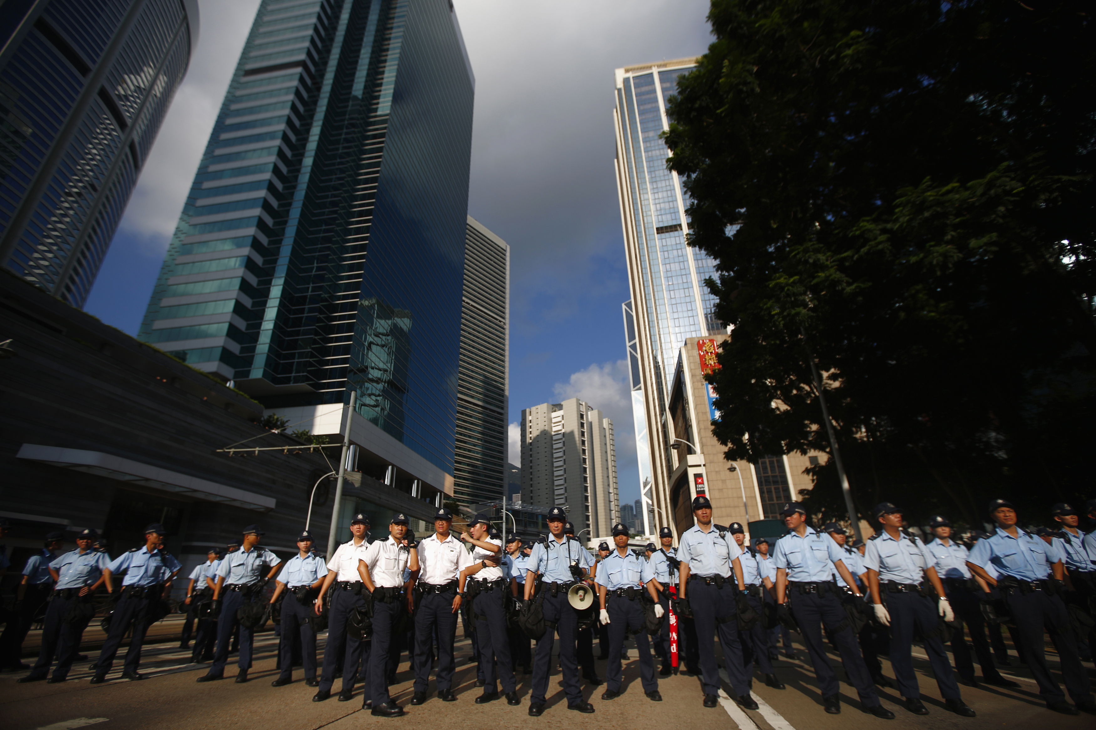 Police officers stand as protesters try to block a street to the financial Central district, near the government headquarters in Hong Kong