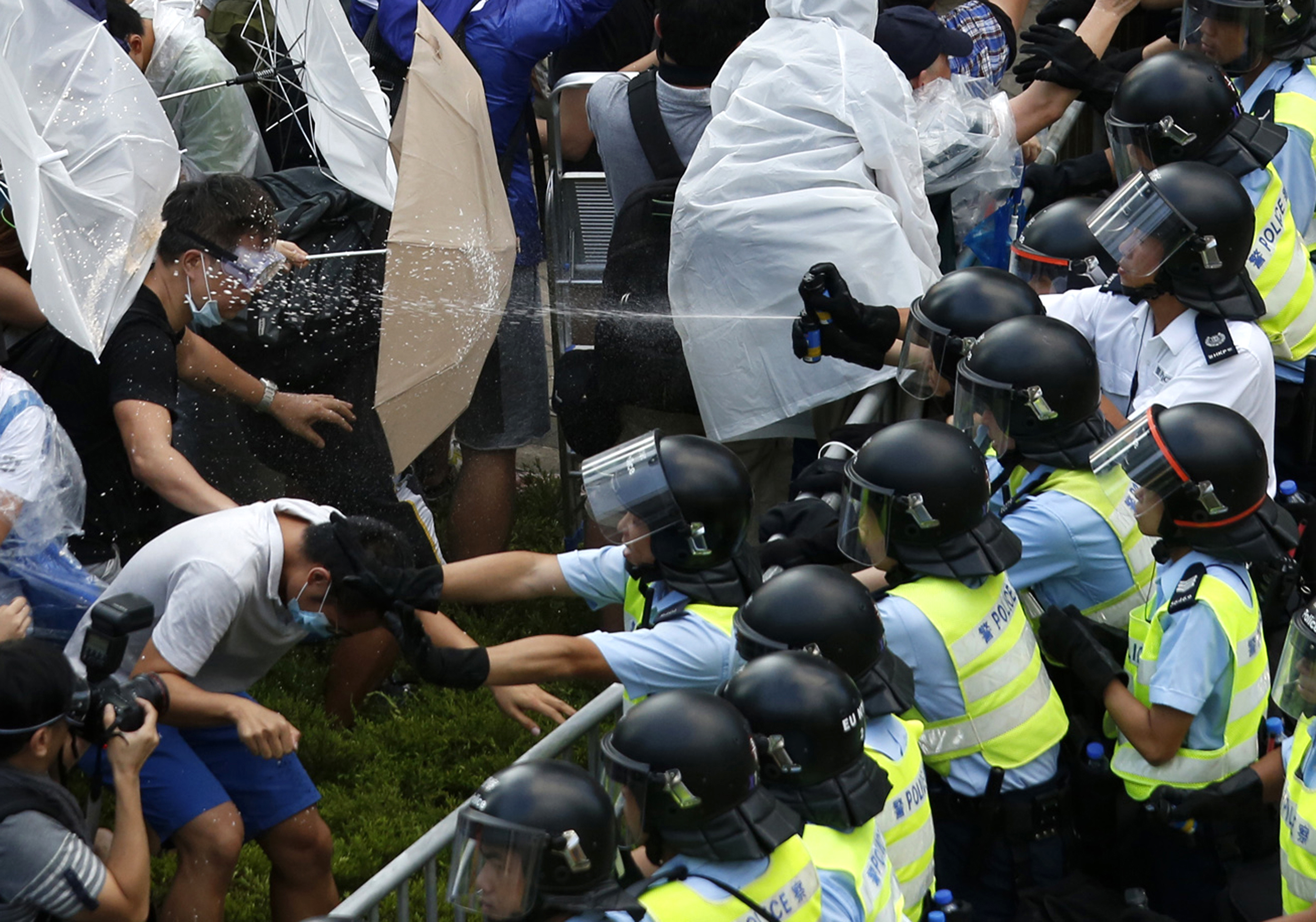 Riot police use pepper spray as they clash with protesters, as tens of thousands of protesters block the main street to the financial Central district outside the government headquarters in Hong Kong