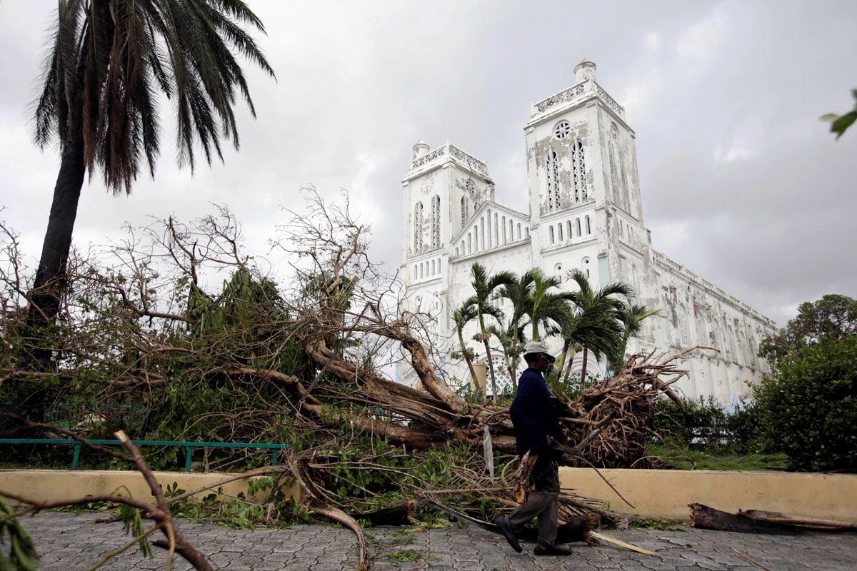 A man carrying branches from fallen trees walks next to the Cathedral after Hurricane Matthew in Les Cayes