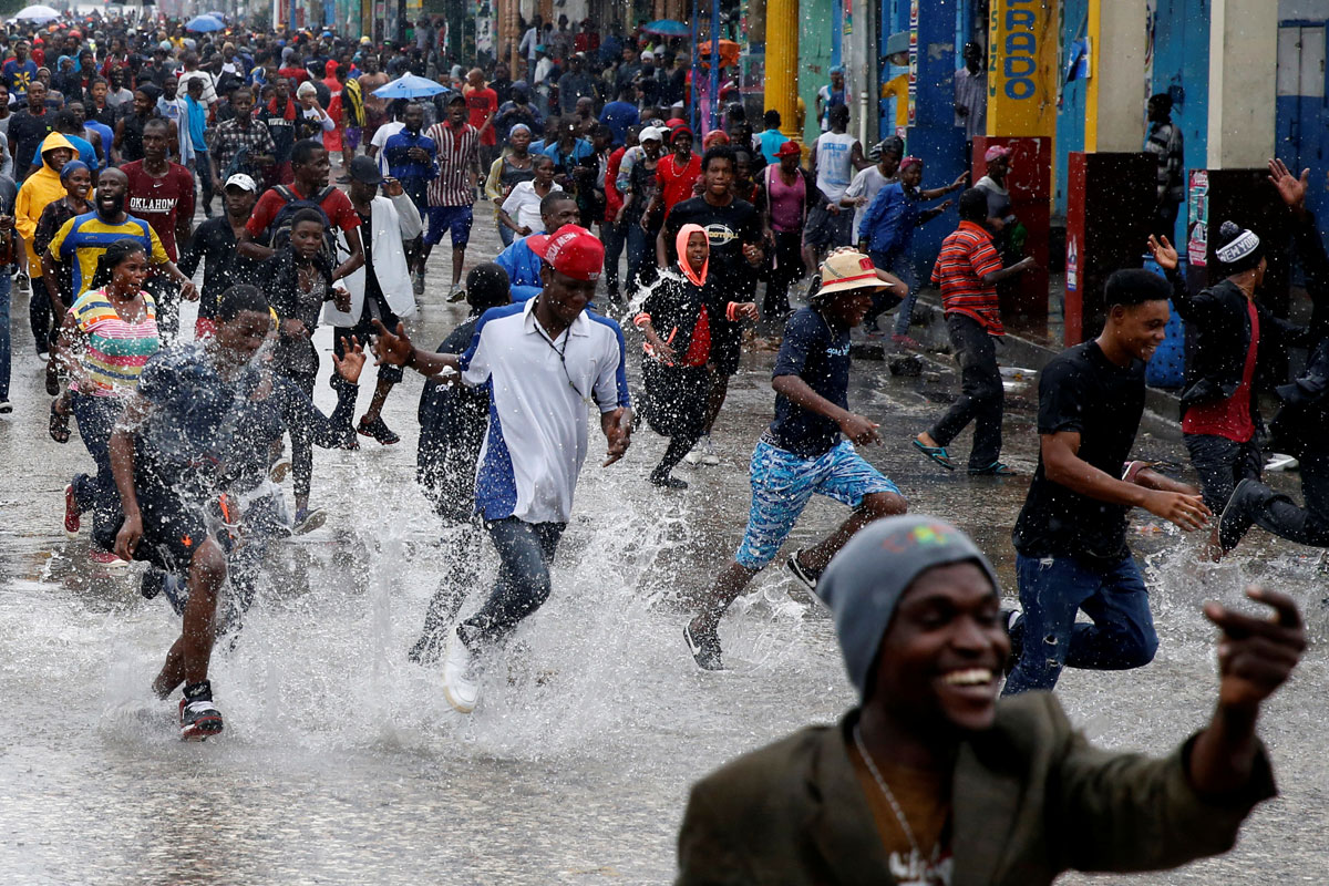 Supporters of Fanmi Lavalas political party splash around in water on a flooded street as they take part in a gathering while Hurricane Matthew passes in Port-au-Prince