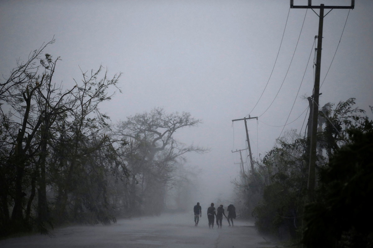 People walk on the road as rain falls during Hurricane Matthew in Les Cayes, Haiti