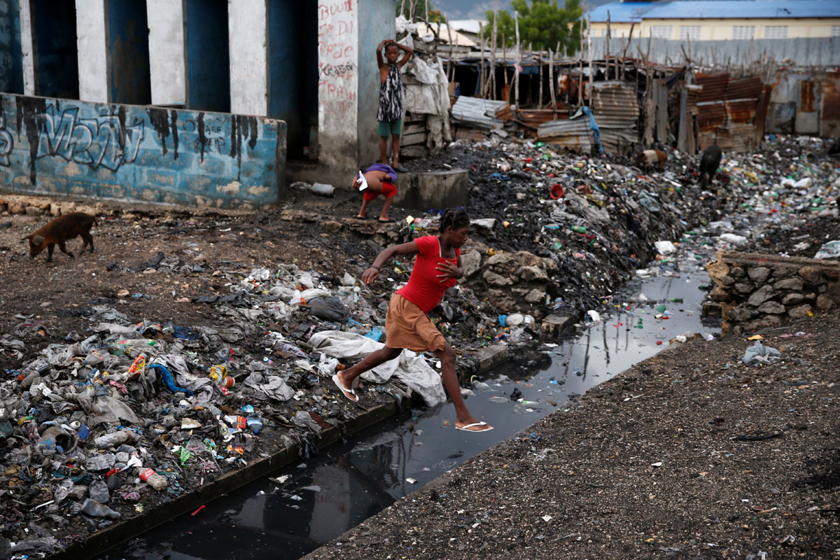 A woman crosses over a water canal after Hurricane Matthew passes Cite-Soleil in Port-au-Prince