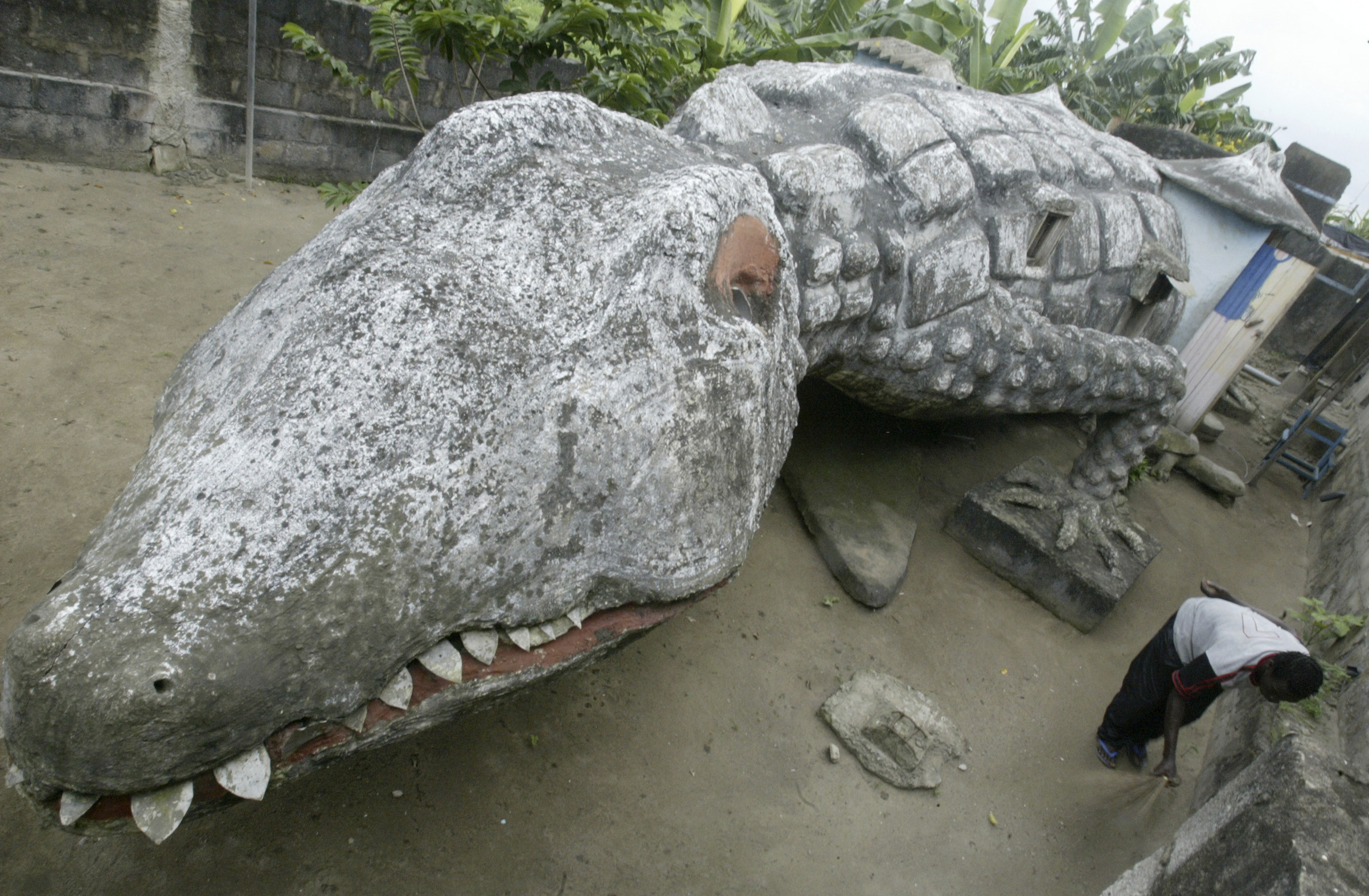 Atta sweeps the courtyard of his house built in the shape of a crocodile in Ivory Coast's capital Abidjan