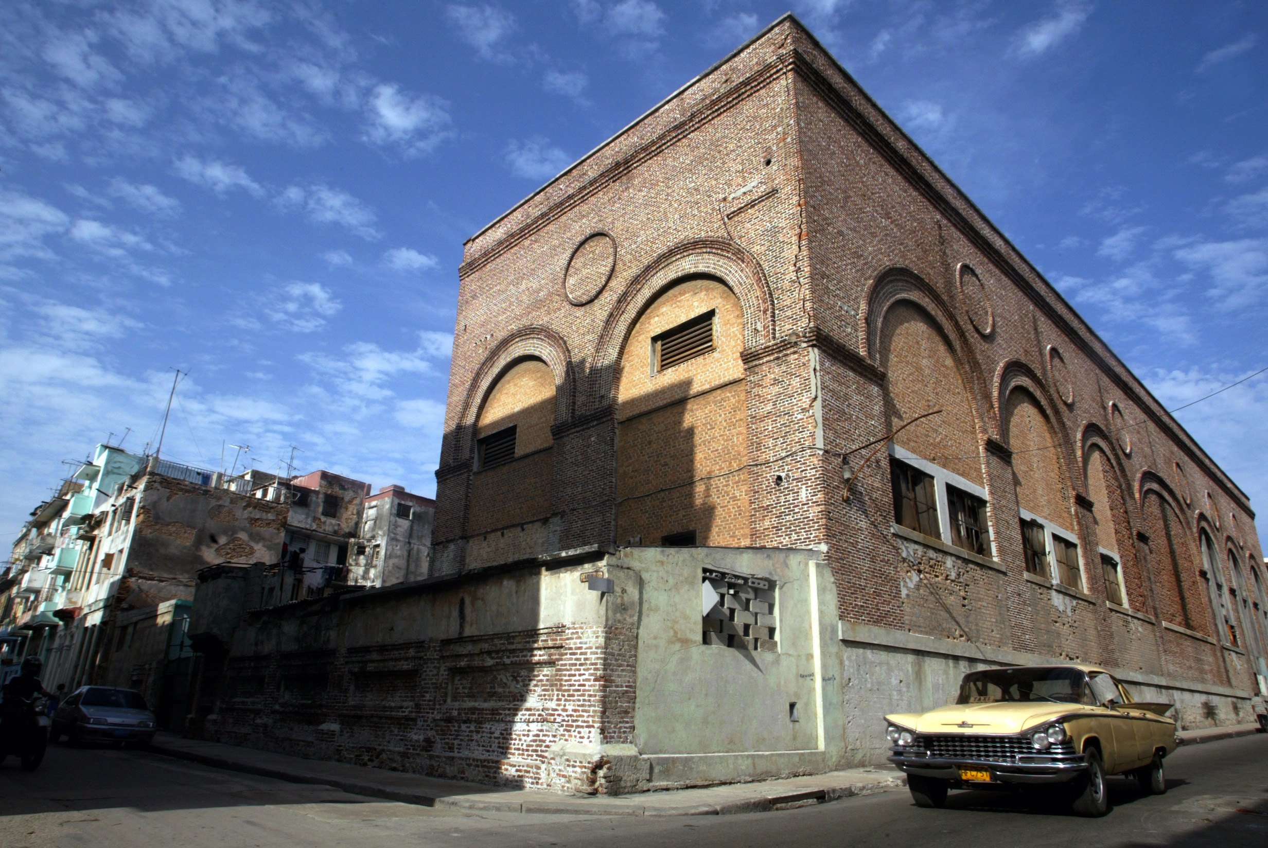 A vintage car drives past a building in Havana