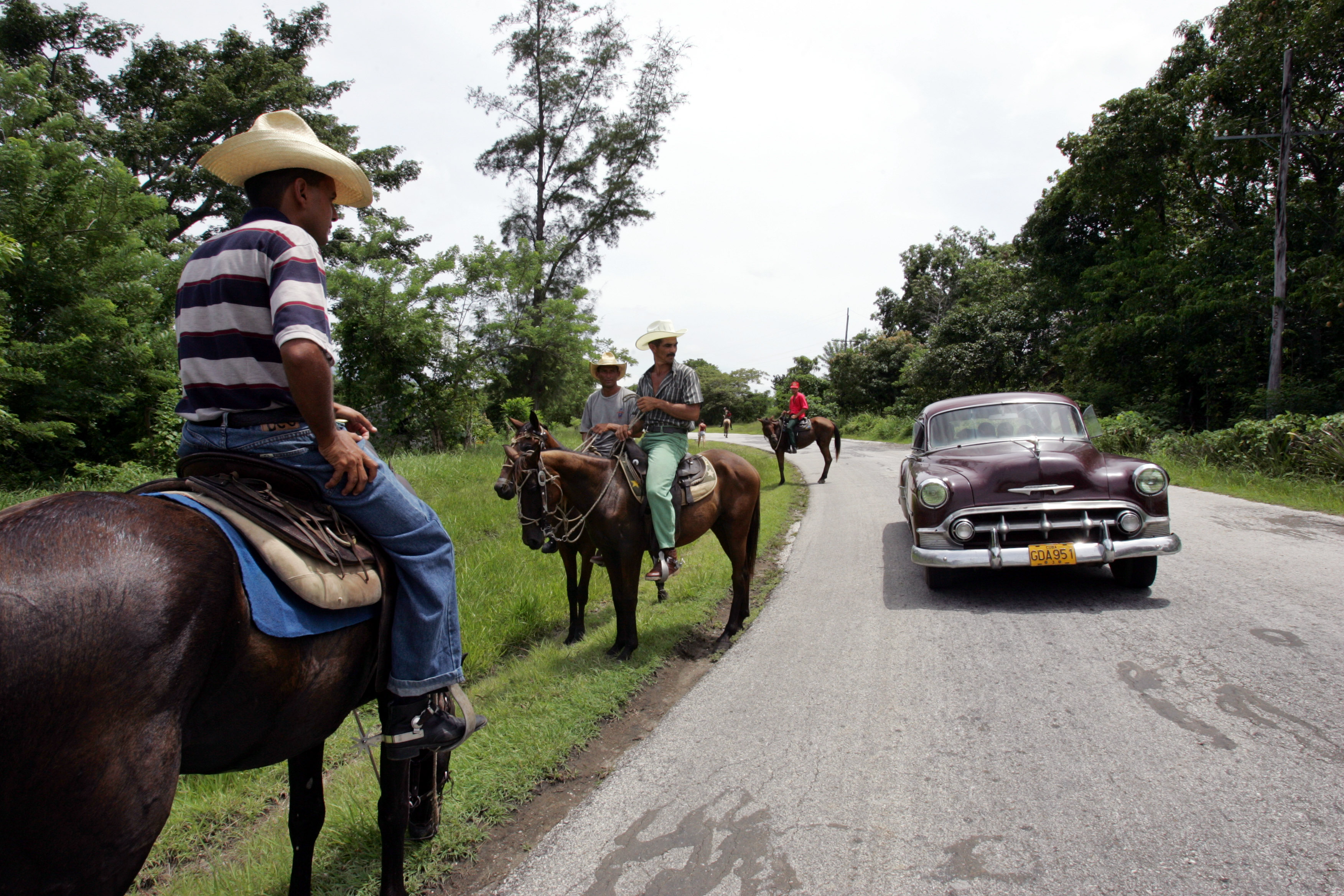 Guajiros on their horses let vintage car drive past on road near Bartolome Maso