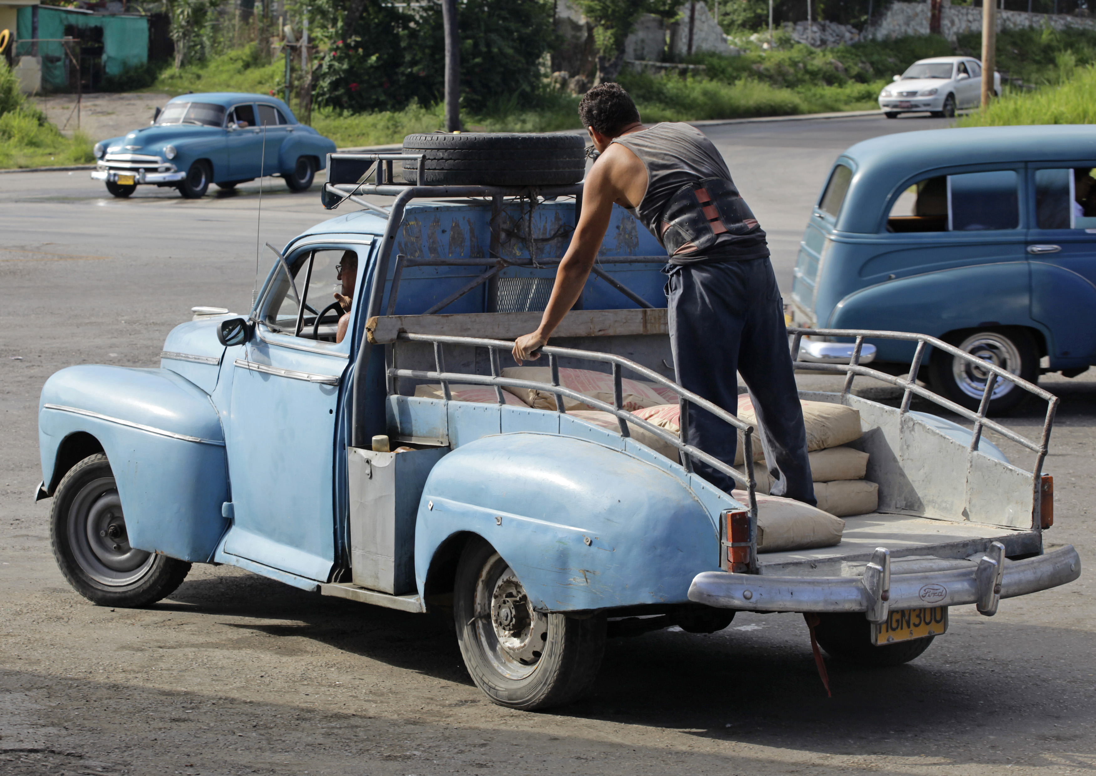 Cuban Gilberto Ruiz drives his modified 1948 Ford Deluxe sedan with a load of cement sacks in Havana