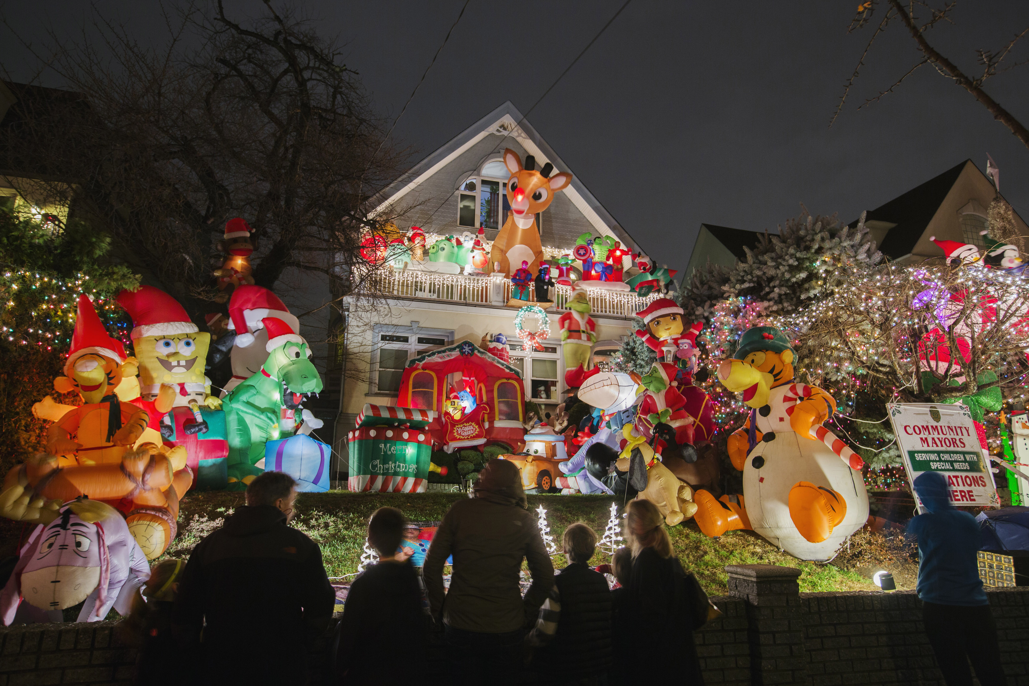 Passerbys look at a house in the Dyker Heights neighborhood of Brooklyn lit up with Christmas decorations in New York