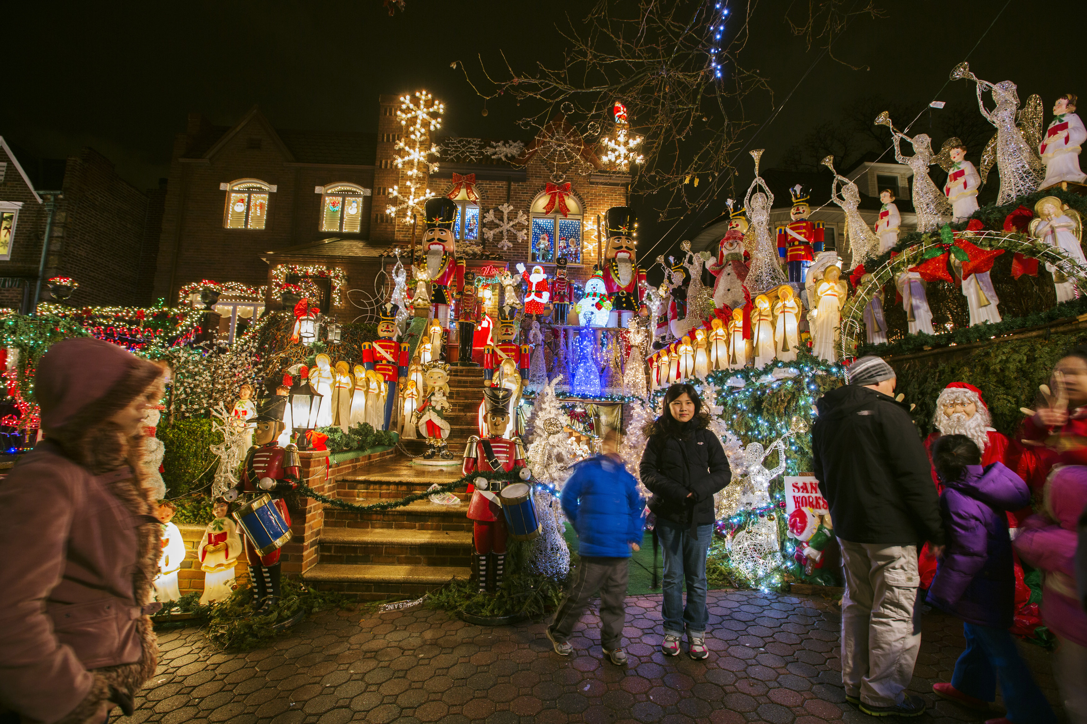 Passerbys stop to have their photograph taken as they look at a house in the Dyker Heights neighborhood of Brooklyn lit up with Christmas decorations in New York