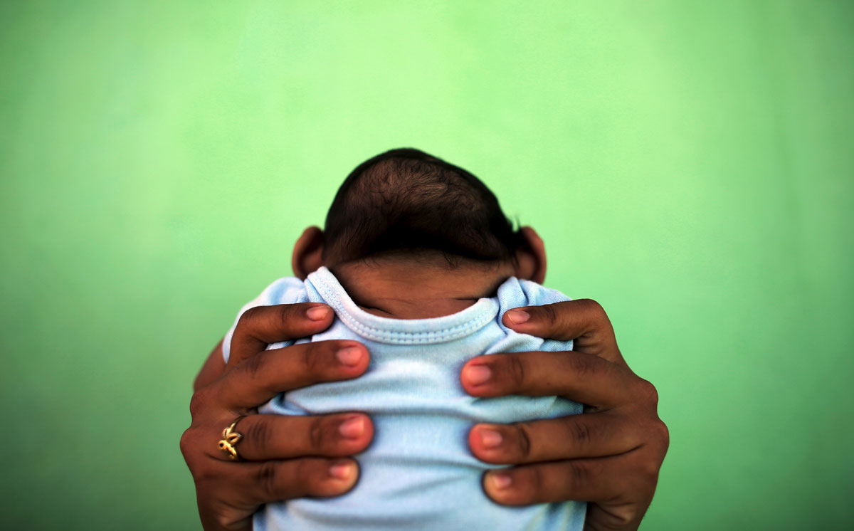 Jackeline, 26, holds her son Daniel who is 4-months old and born with microcephaly, in front of their house in Olinda