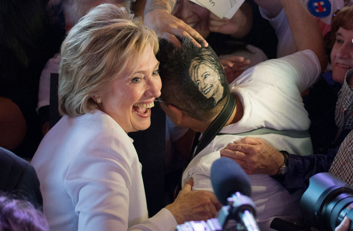 Democratic presidential candidate Clinton poses for a picture with supporter Monsivaiz who has her hair styled with Clinton's image at a rally in San Antonio, Texas