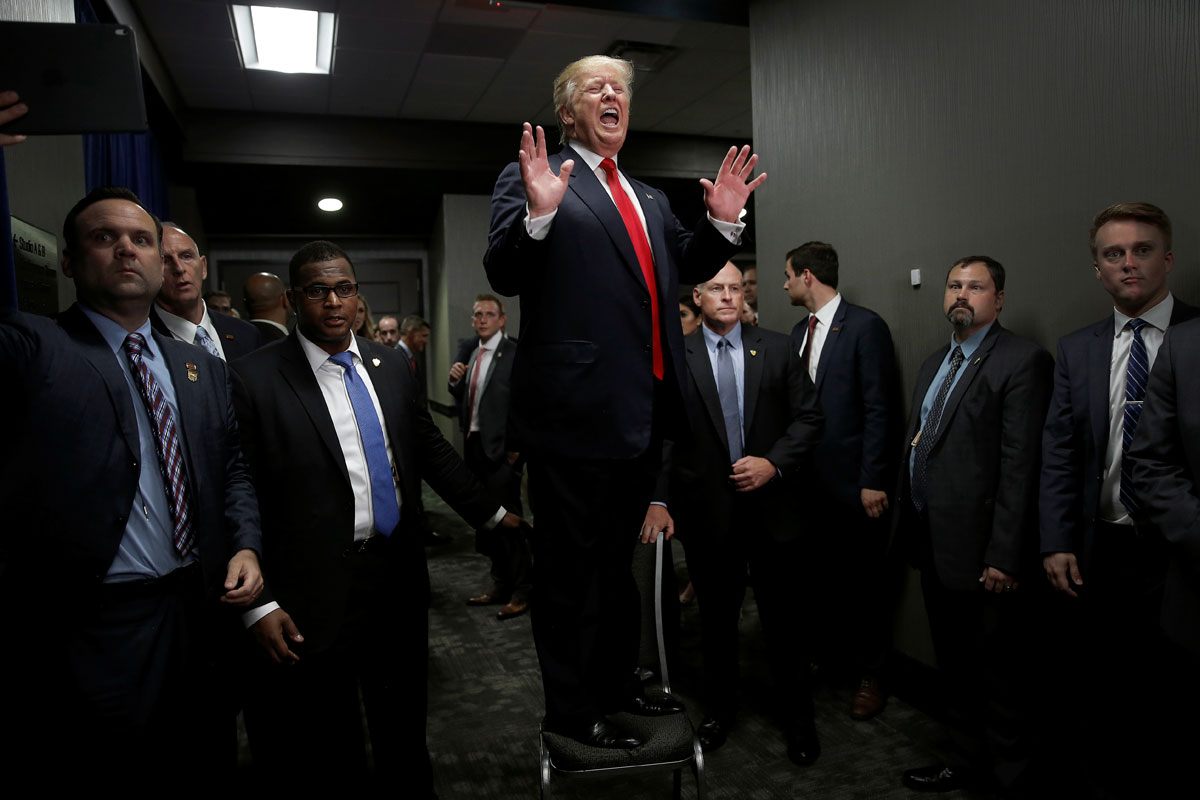 Republican presidential nominee Donald Trump stands on a chair to speak to people in an overflow area after a campaign rally in Greenville