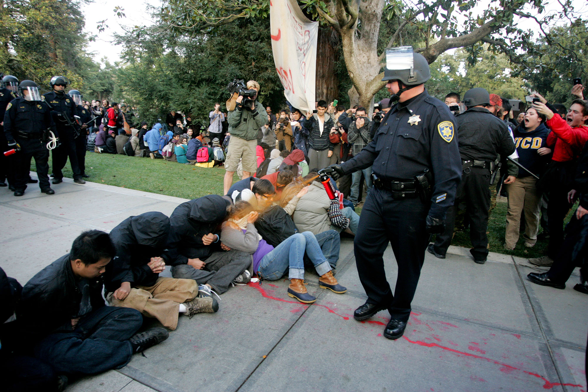 A University of California Davis police officer pepper-sprays students during their sit-in at an "Occupy UCD" demonstration in Davis