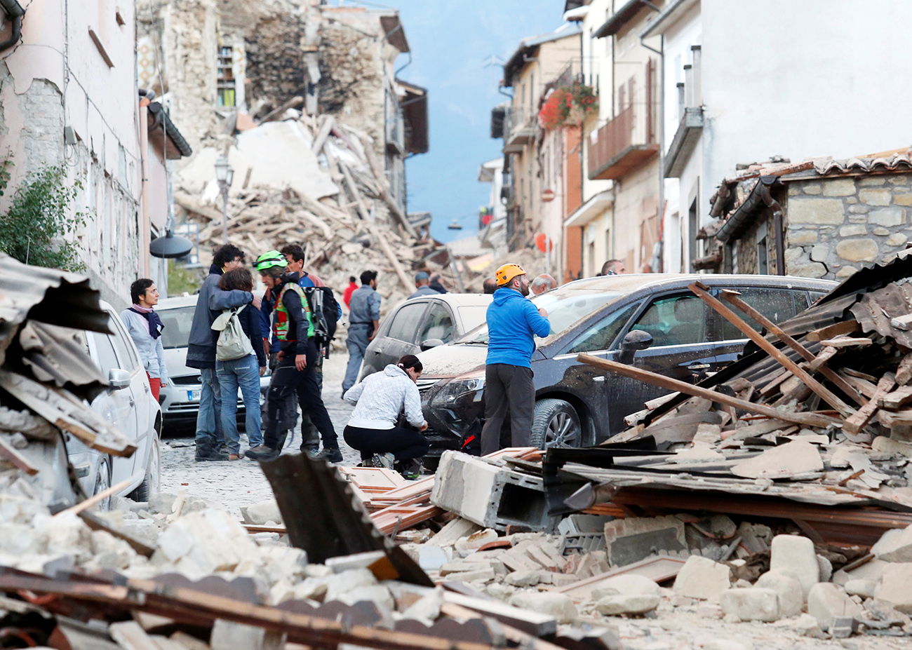 People stand along a road following a quake in Amatrice