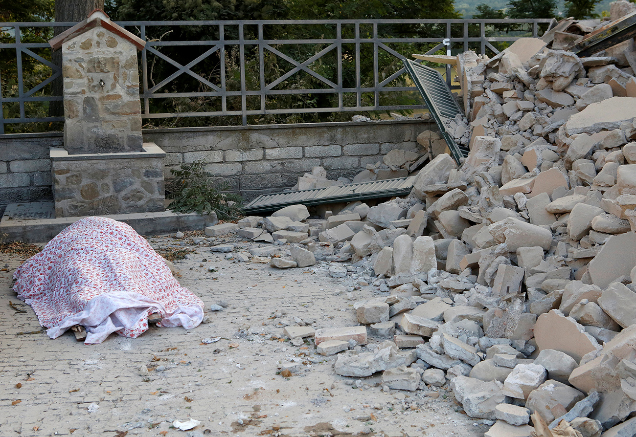  A body is covered by cloth next to rubble following a quake in Amatrice 