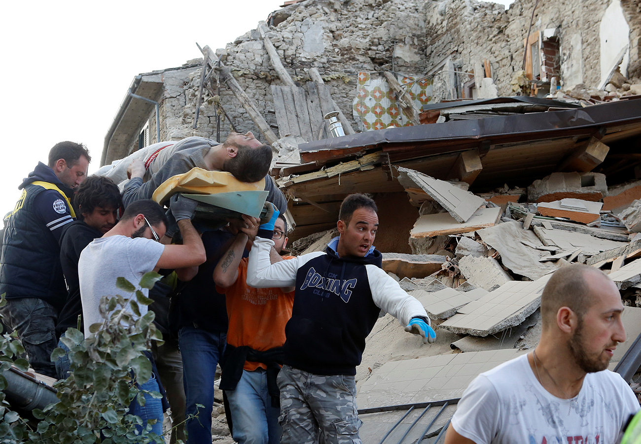 A man is carried away after having been rescued alive from the ruins following an earthquake in Amatrice