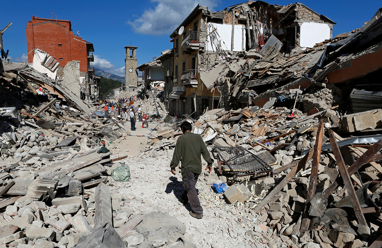 A man walks amidst rubble following an earthquake in Pescara del Tronto