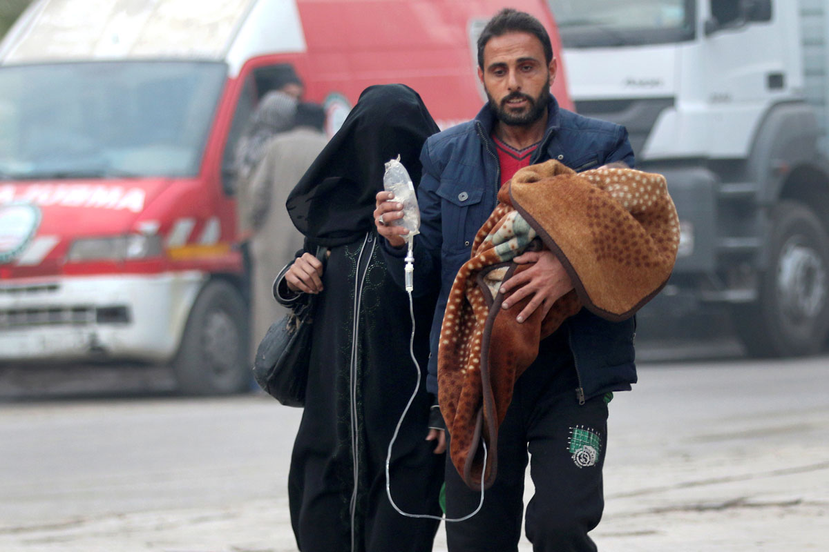 A man carries a child with an IV drip as he flees deeper into the remaining rebel-held areas of Aleppo