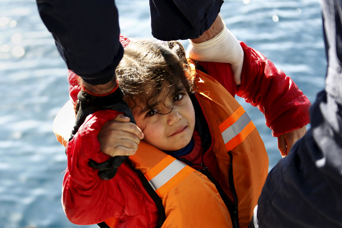 Greek Coast Guard officers move a girl from a dinghy carrying refugees and migrants aboard the Ayios Efstratios Coast Guard vessel,  during a rescue operation at open sea between the Turkish coast and the Greek island of Lesbos