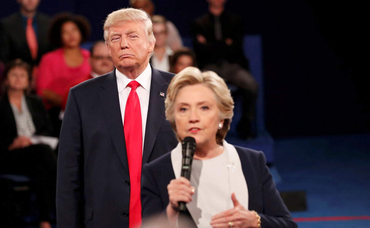 Republican U.S. presidential nominee Trump listens as Democratic nominee Clinton answers a question from the audience during their presidential town hall debate in St. Louis