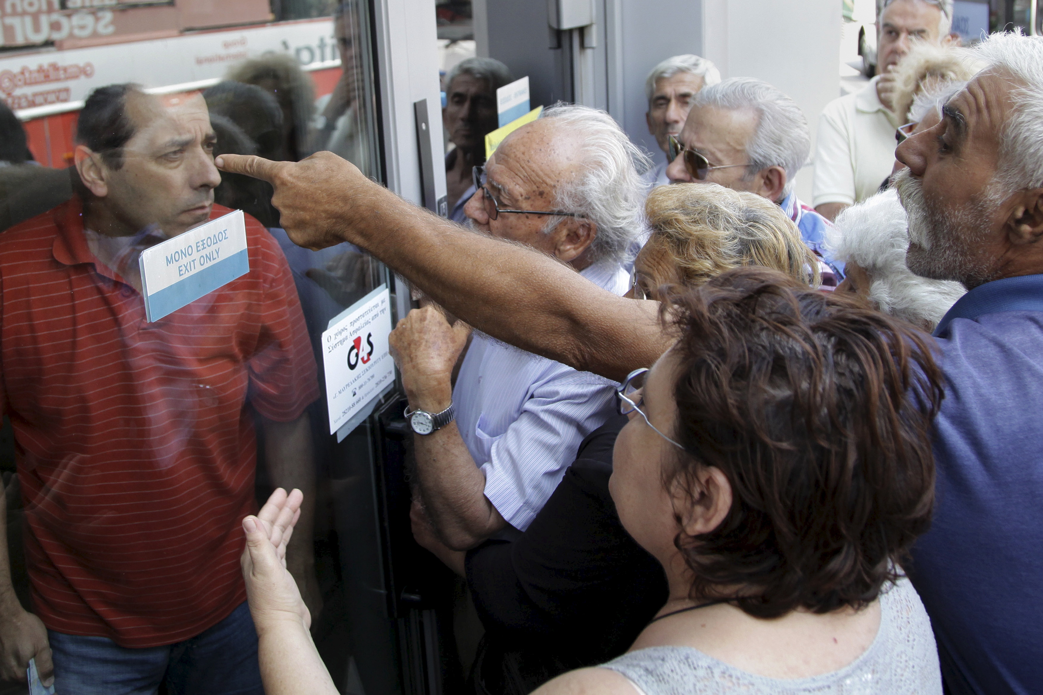 Pensioners waiting outside a closed National Bank branch and hoping to get their pensions, argue with a bank employee in Iraklio on the island of Crete