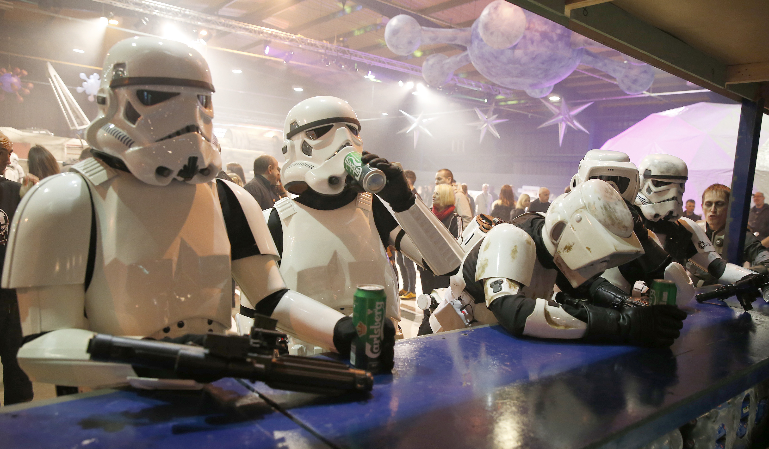 People dressed as Storm troopers stand at a bar as they pose for a photograph holding cans of beer at the  'For The Love of The Force' Star Wars fan convention in Manchester , northern England