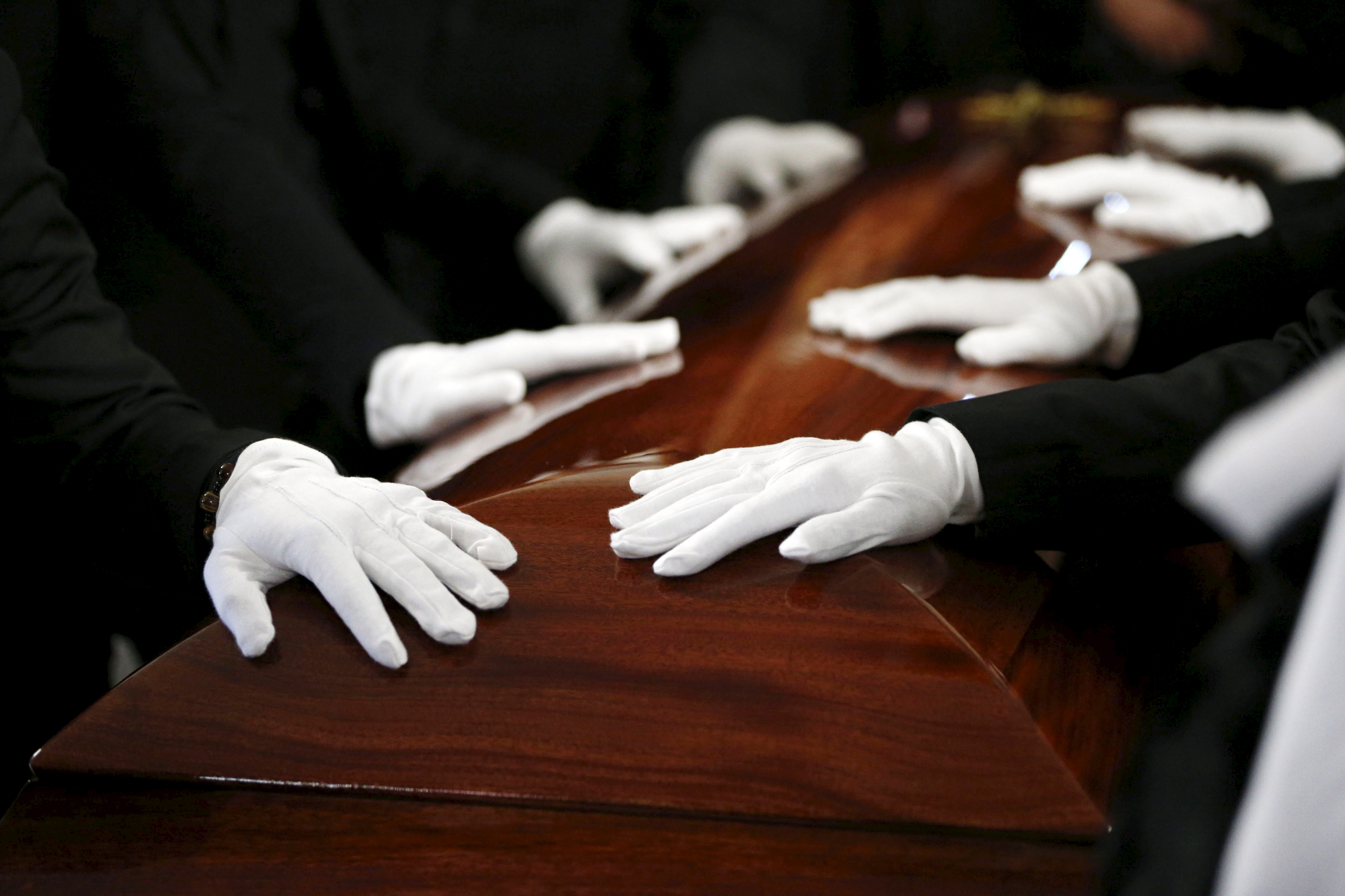 Pallbearers rest their hands on the casket of San Bernardino shooting victim Tin Nguyen during her funeral at Saint Barbara's Catholic Church in Santa Ana, California