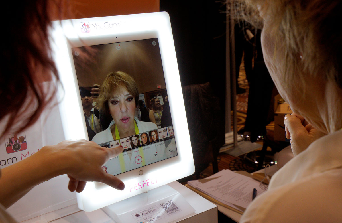 A show-goer tries out the YouCam Makeup mirror which shows different make up without actually applying any in at CES in Las Vegas