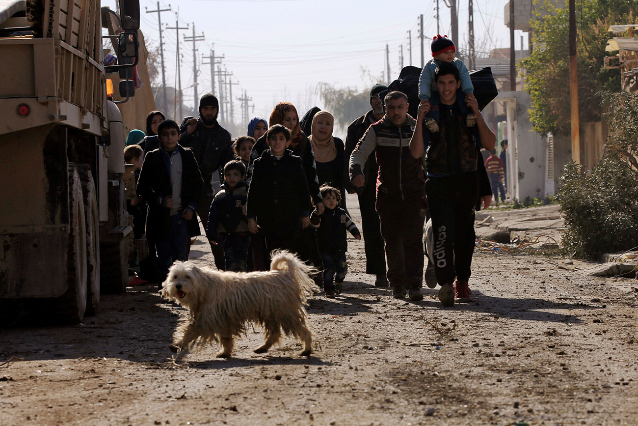 Iraqi people, who are fleeing from clashes, walk with their children during a battle with Islamic State militants, eastern Mosul