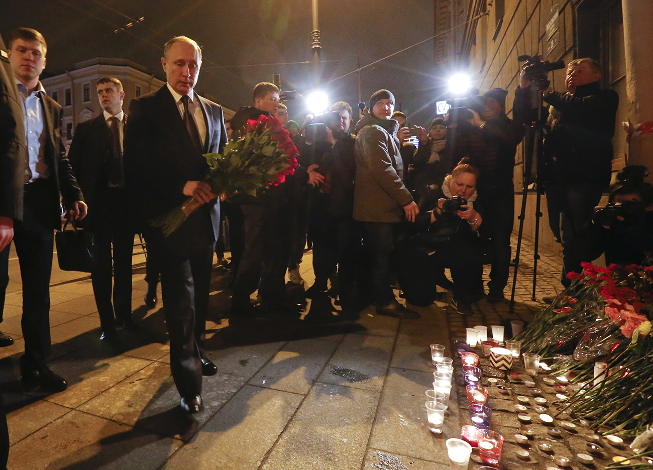 Russian president Vladimir Putin puts flowers down outside Tekhnologicheskiy Institut metro station in St. Petersburg
