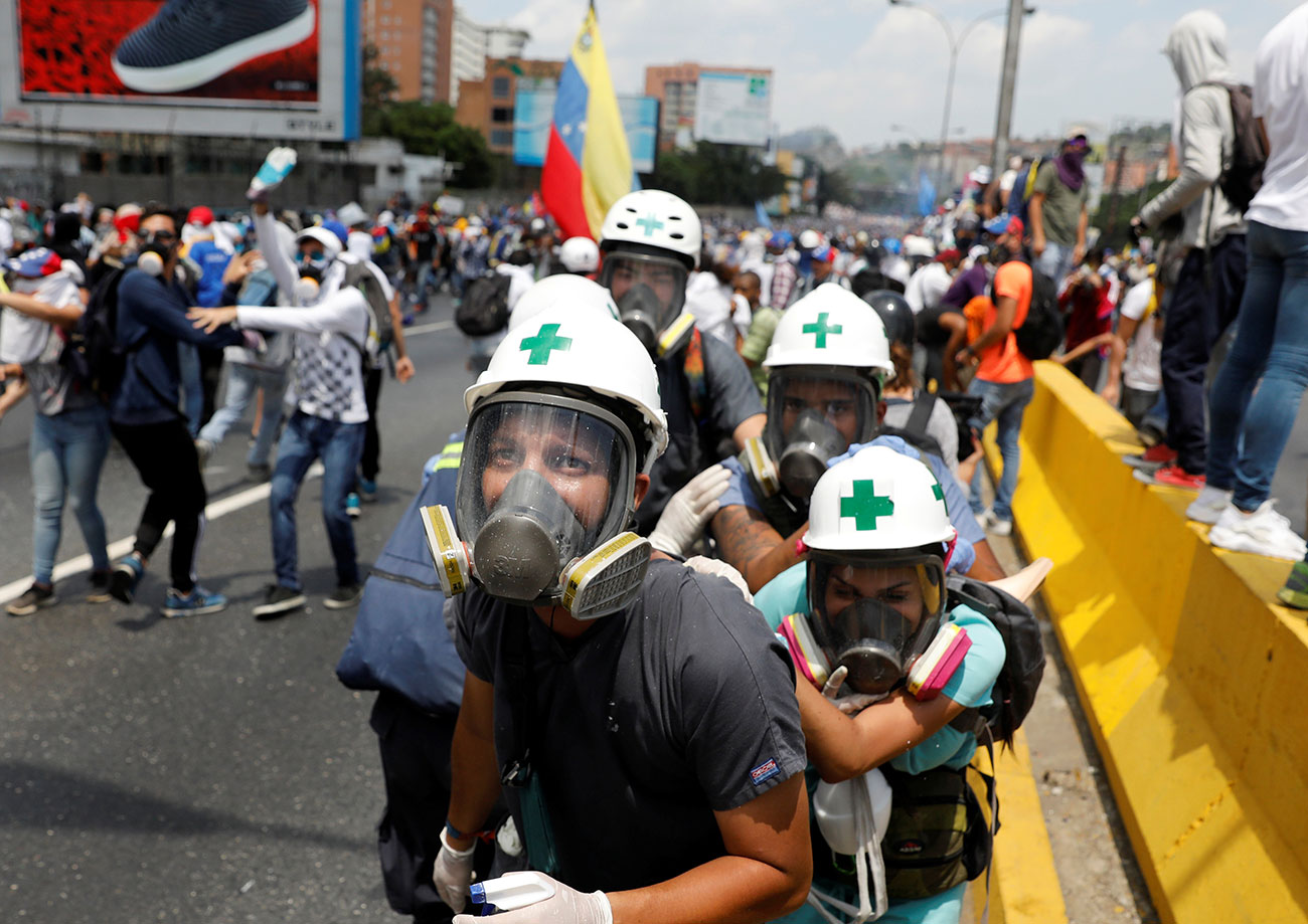 Volunteers, members of a primary care response team, huddle together during clashes with security forces at a rally against Venezuela's President Nicolas Maduro in Caracas