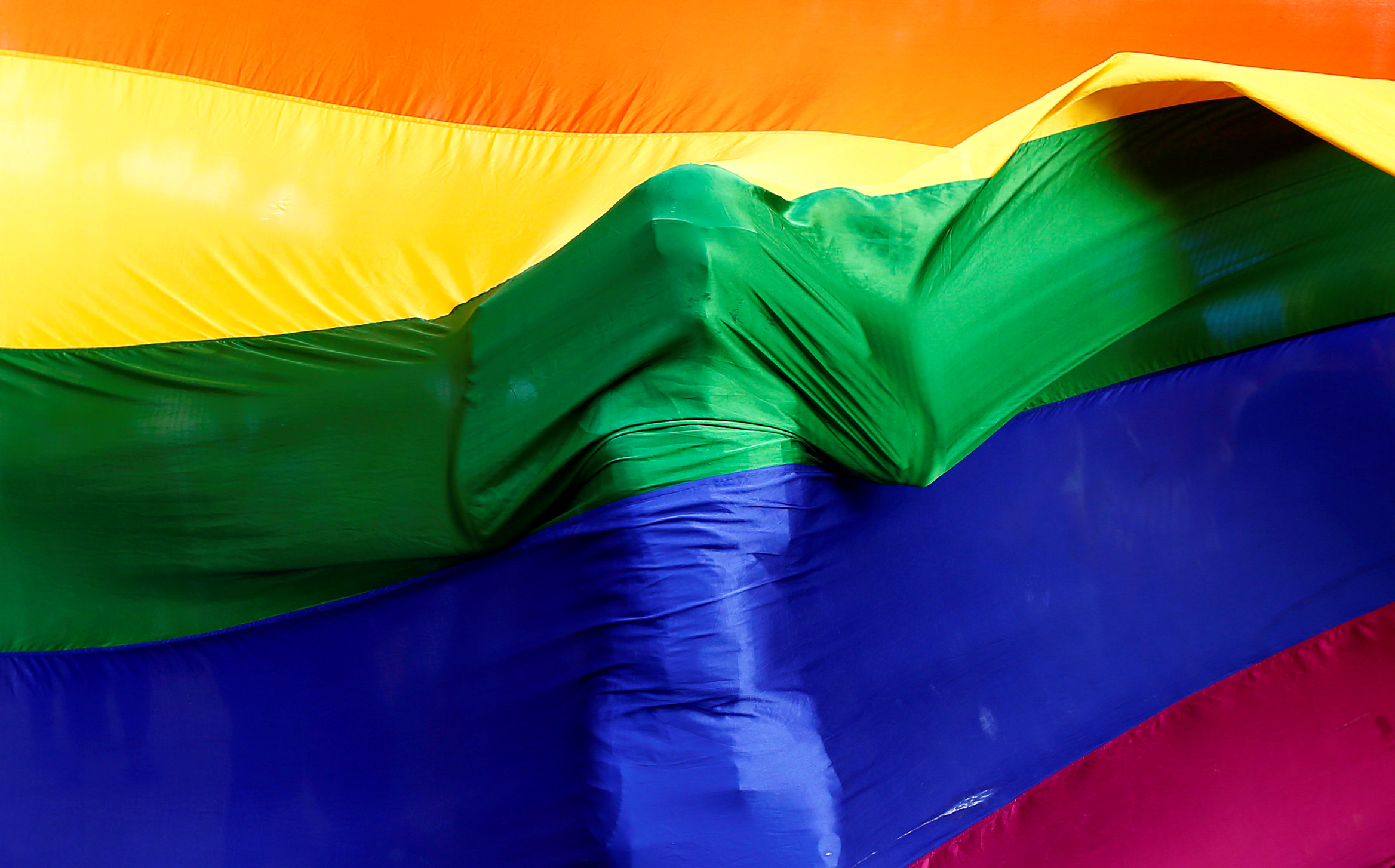 A participant stands behind a rainbow flag during a vigil in memory of the victims of the Pulse gay nightclub shooting in Orlando, Florida, in Mumbai